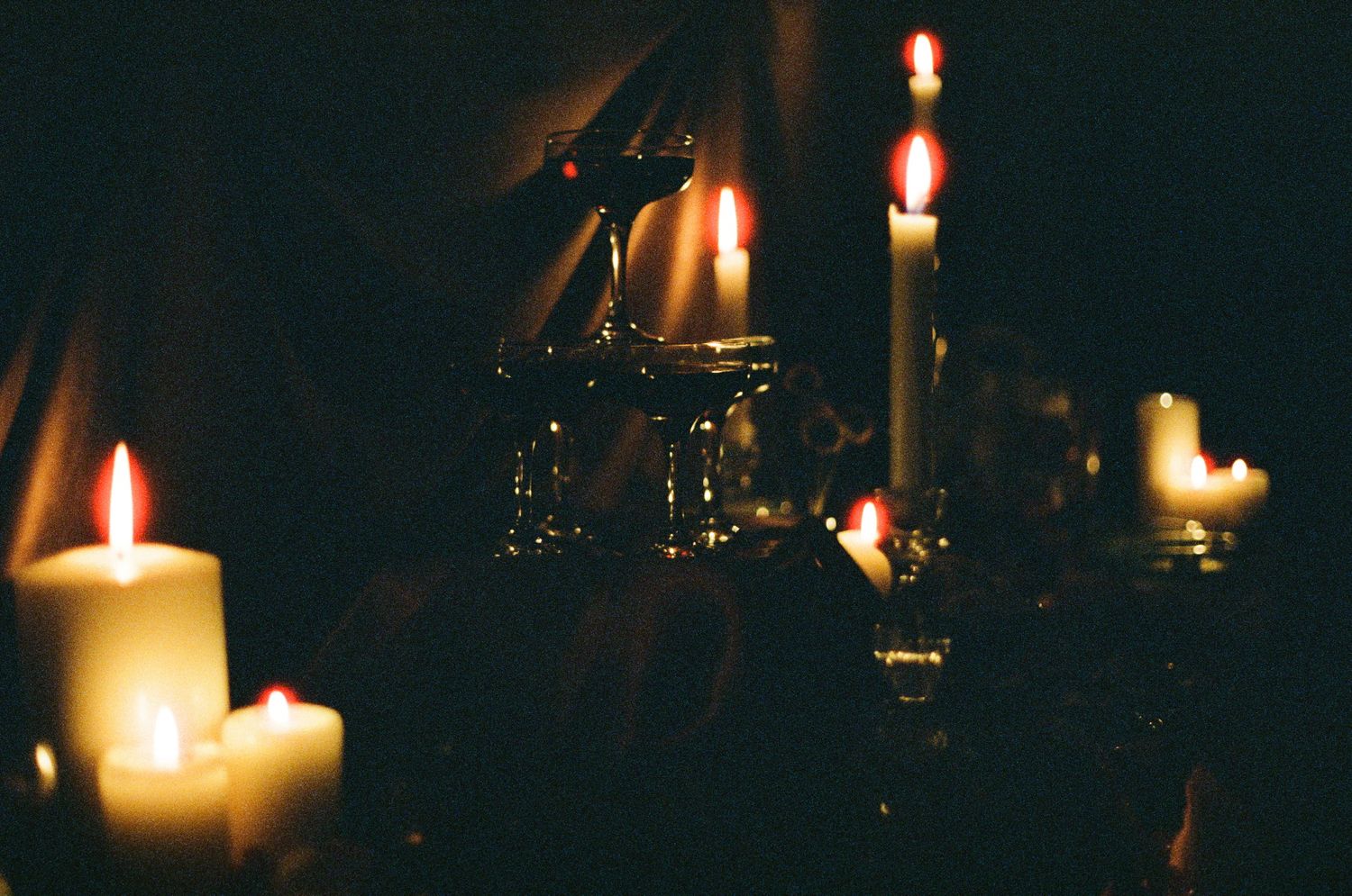 Candlelight casts a warm glow across a darkened space with scattered illuminated points.
