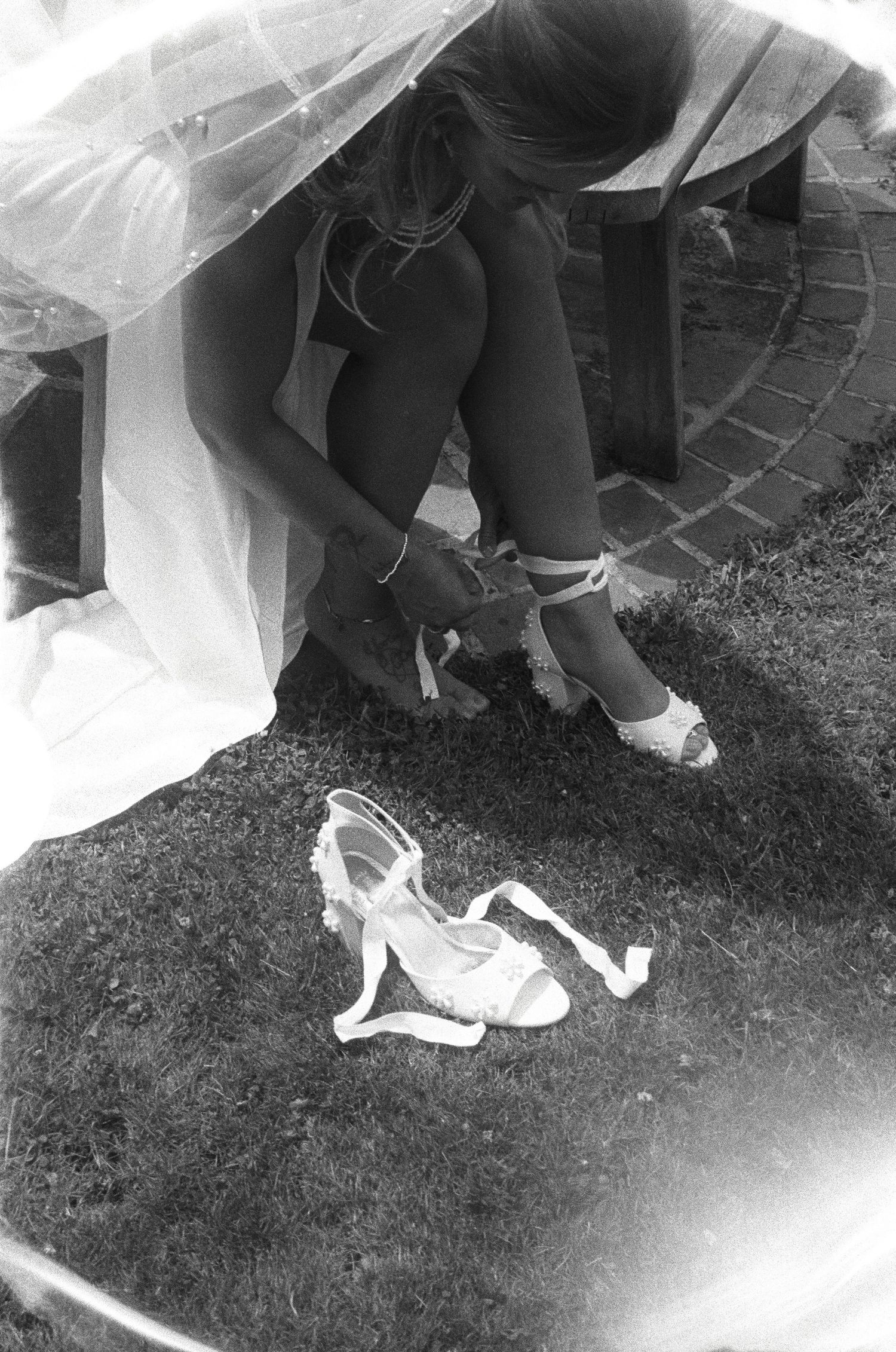 Close-up of bride's white shoes and dress hem on grass.