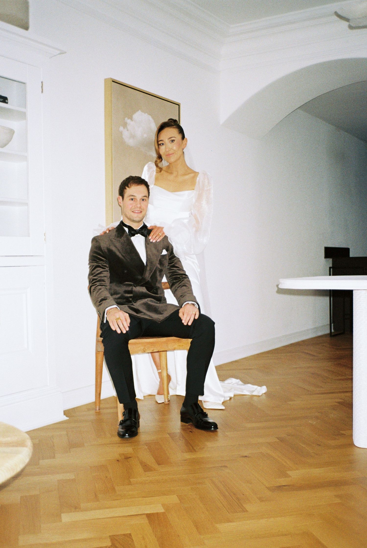 Person in formal attire seated on wooden floor in white room showing sequence of movement.