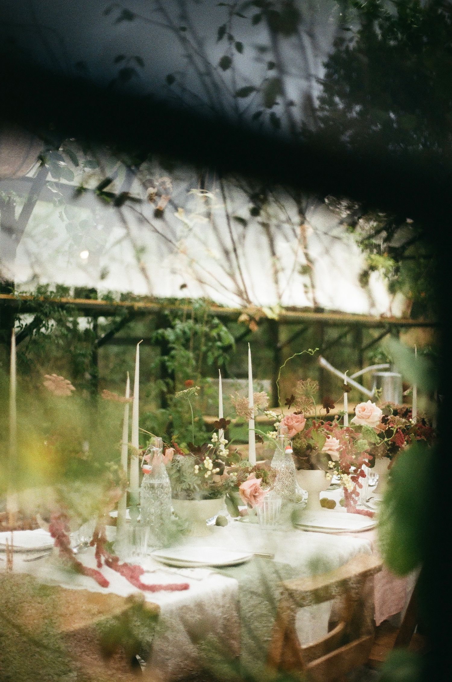 Elegant table settings with white linens and candles for a romantic outdoor dinner party.
