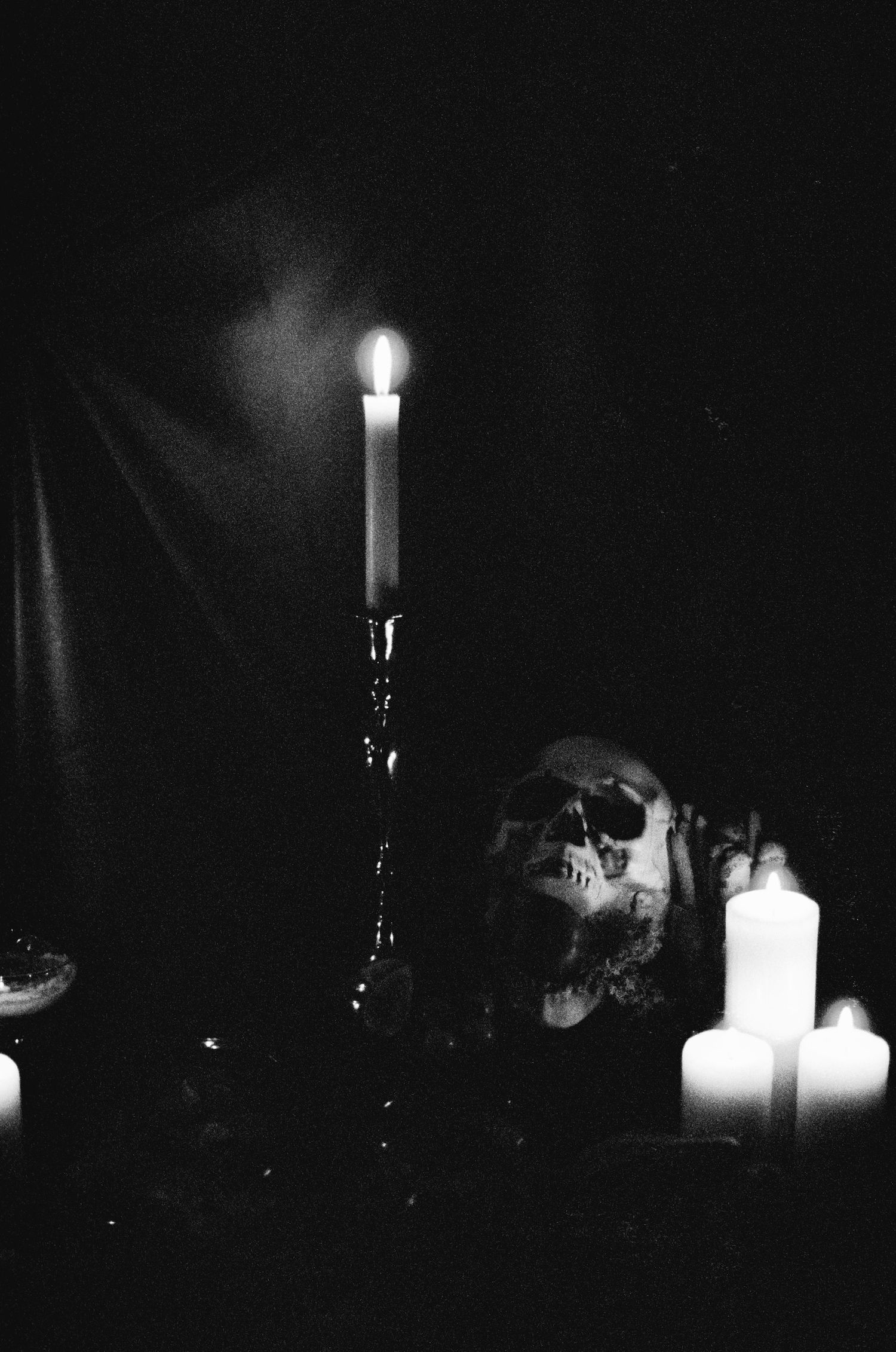 White candles glow softly in a dark room creating a mysterious ambiance.