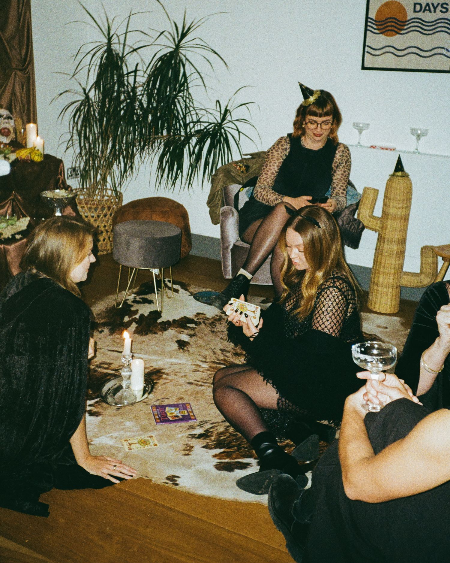 People sit together at a casual indoor gathering with Halloween decorations and ambient lighting.