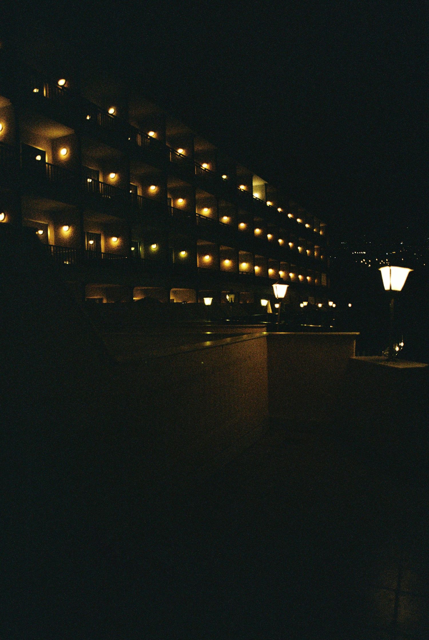 Row of illuminated street lamps creating a glowing path in the darkness.
