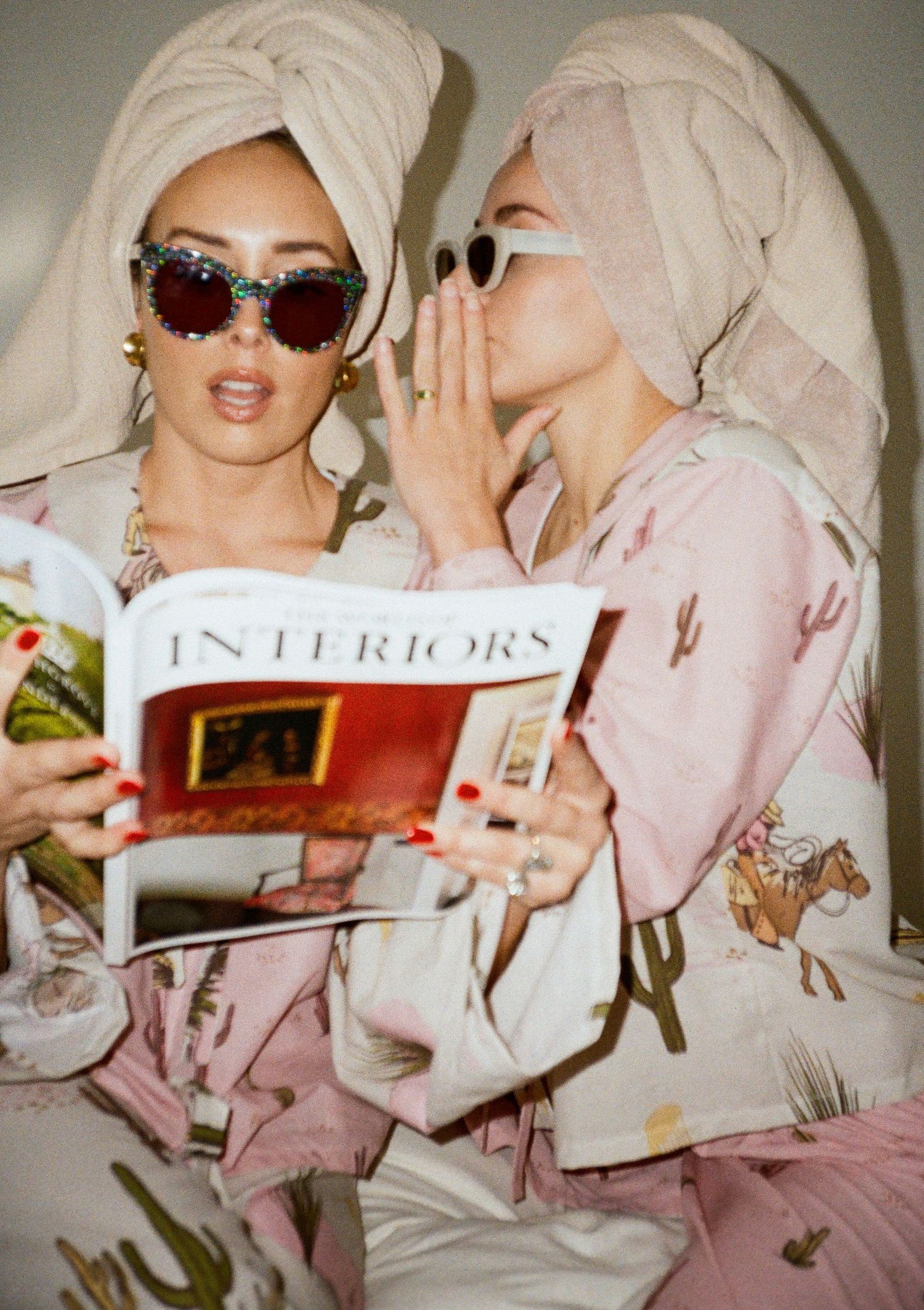 People in pink robes reading interior design magazines while wearing sunglasses.