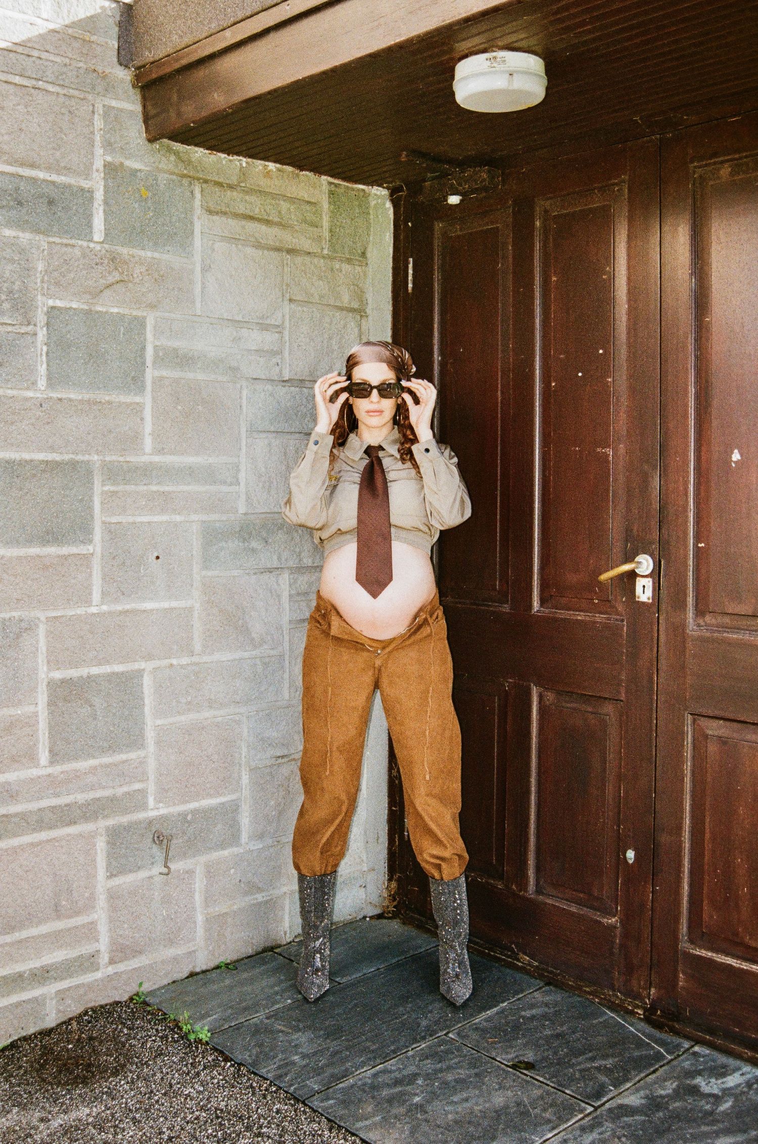 Series of photos showing someone playfully hiding behind a dark wooden door in a brick building.