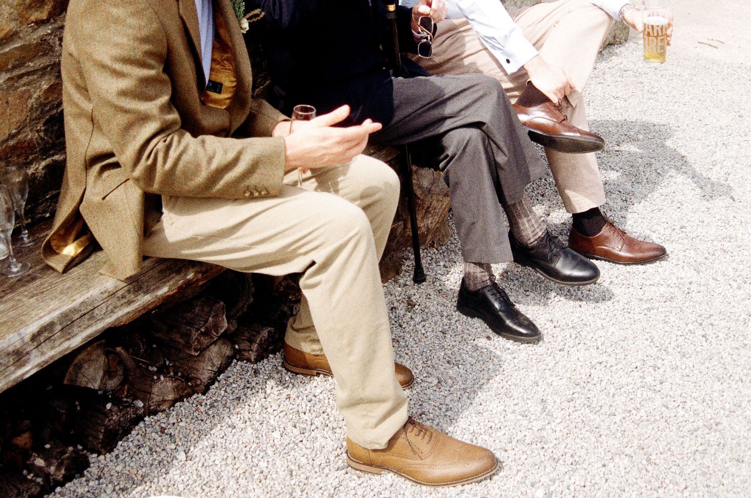 Detail shot of wedding guests' feet and formal shoes on gravel ground.