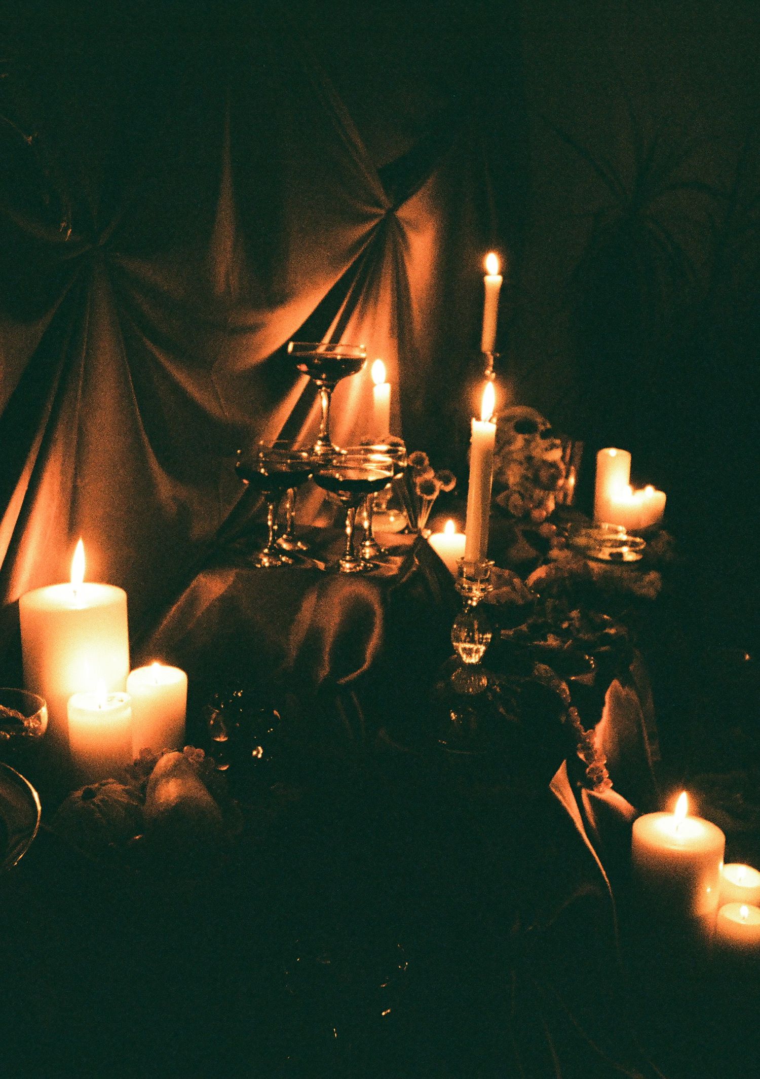 Moody candlelit Halloween scene with glowing flames illuminating decorations in the darkness.