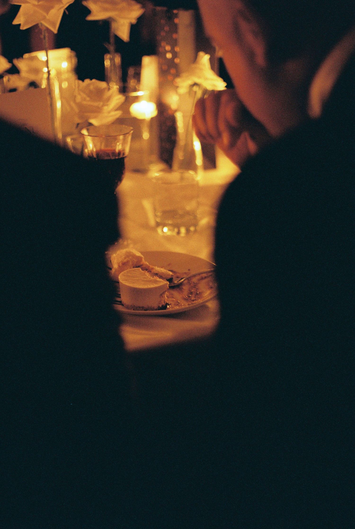 Candlelit table settings create a warm ambiance in a dimly lit restaurant interior with glowing yellow lights.