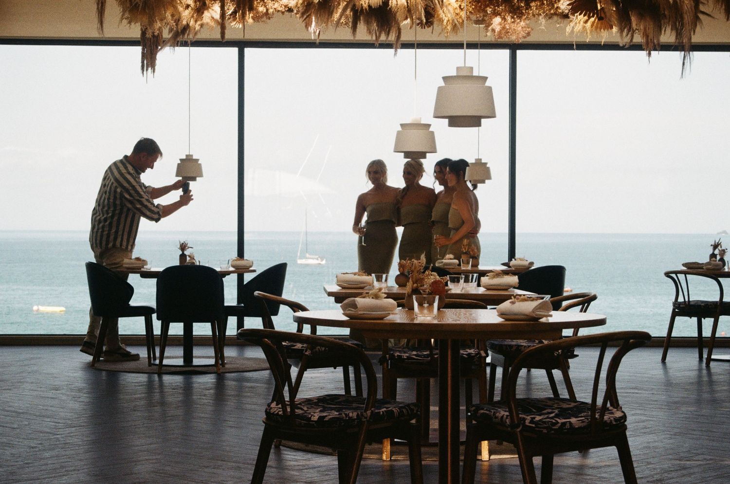 Silhouettes of diners at an oceanfront restaurant during sunset.