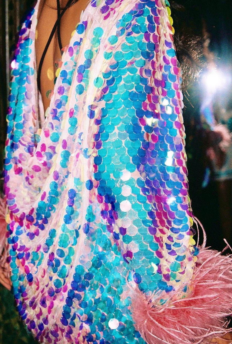 Shimmering sequined fabric in turquoise, purple and pink creates a dazzling pattern.