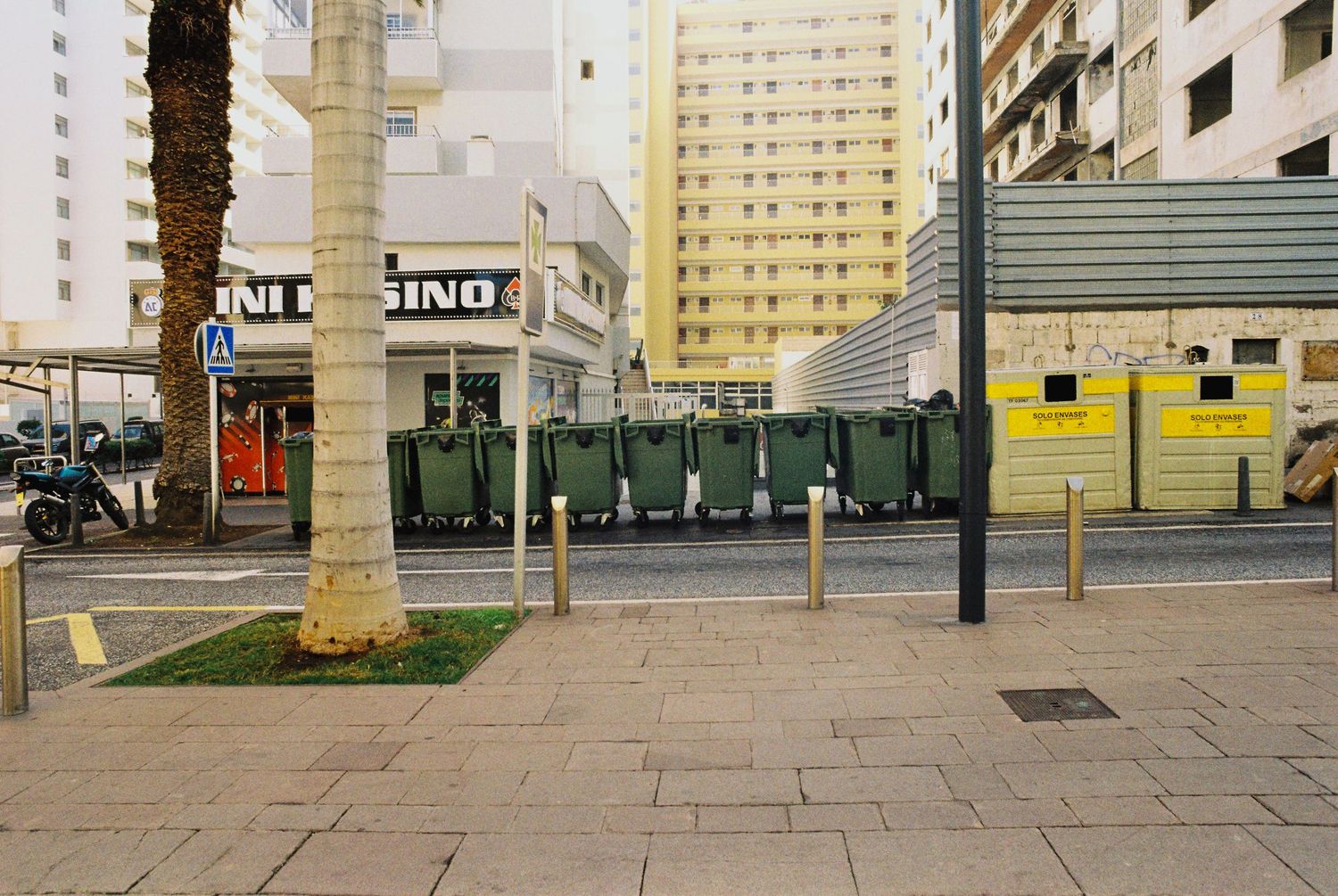 Urban plaza with yellow apartment buildings and concrete walkways in a modern city setting.