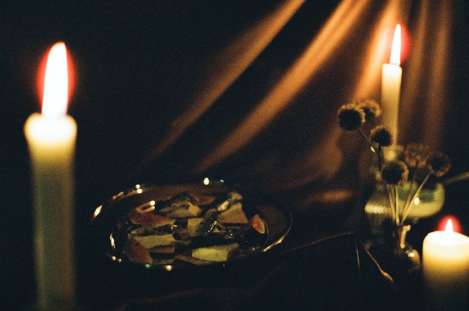 Row of glowing candles creating atmospheric lighting against dark background.