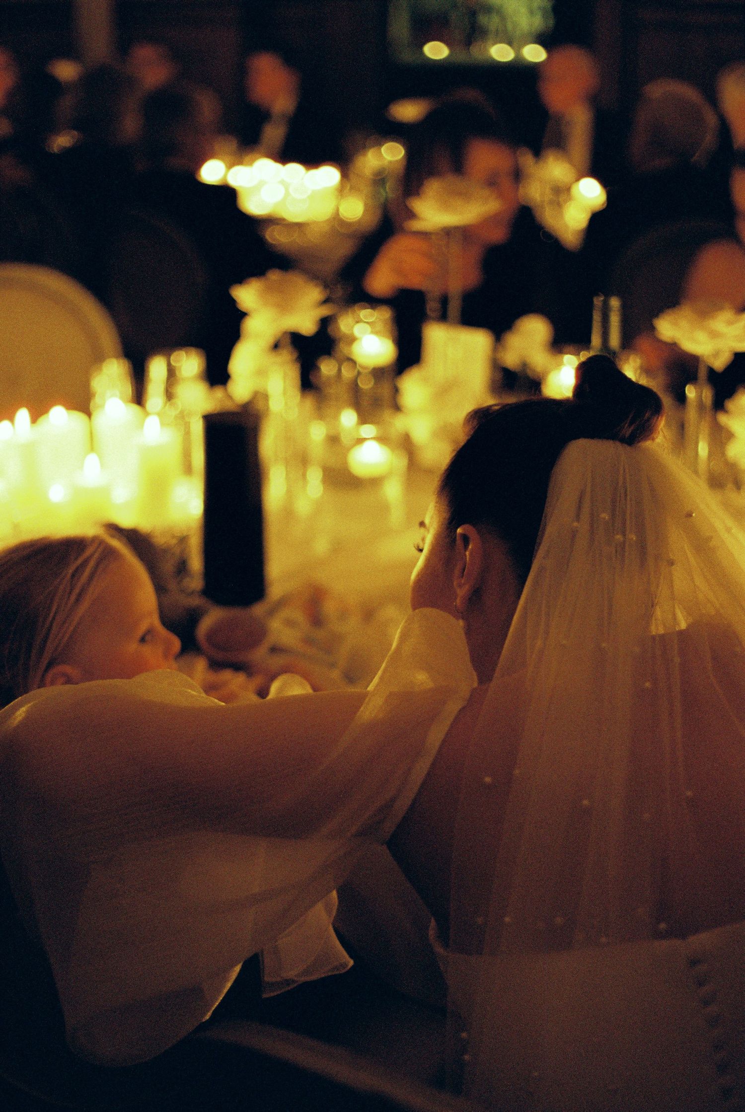 Candlelit wedding reception tables glow warmly in a dimly lit venue with romantic ambiance.