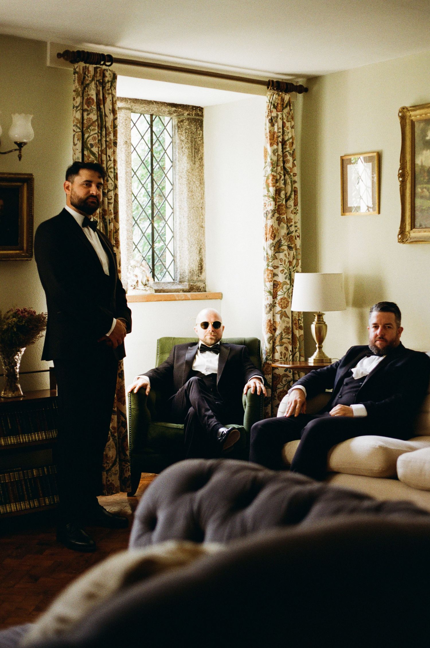 Men in formal attire seated in an elegant living room setting.