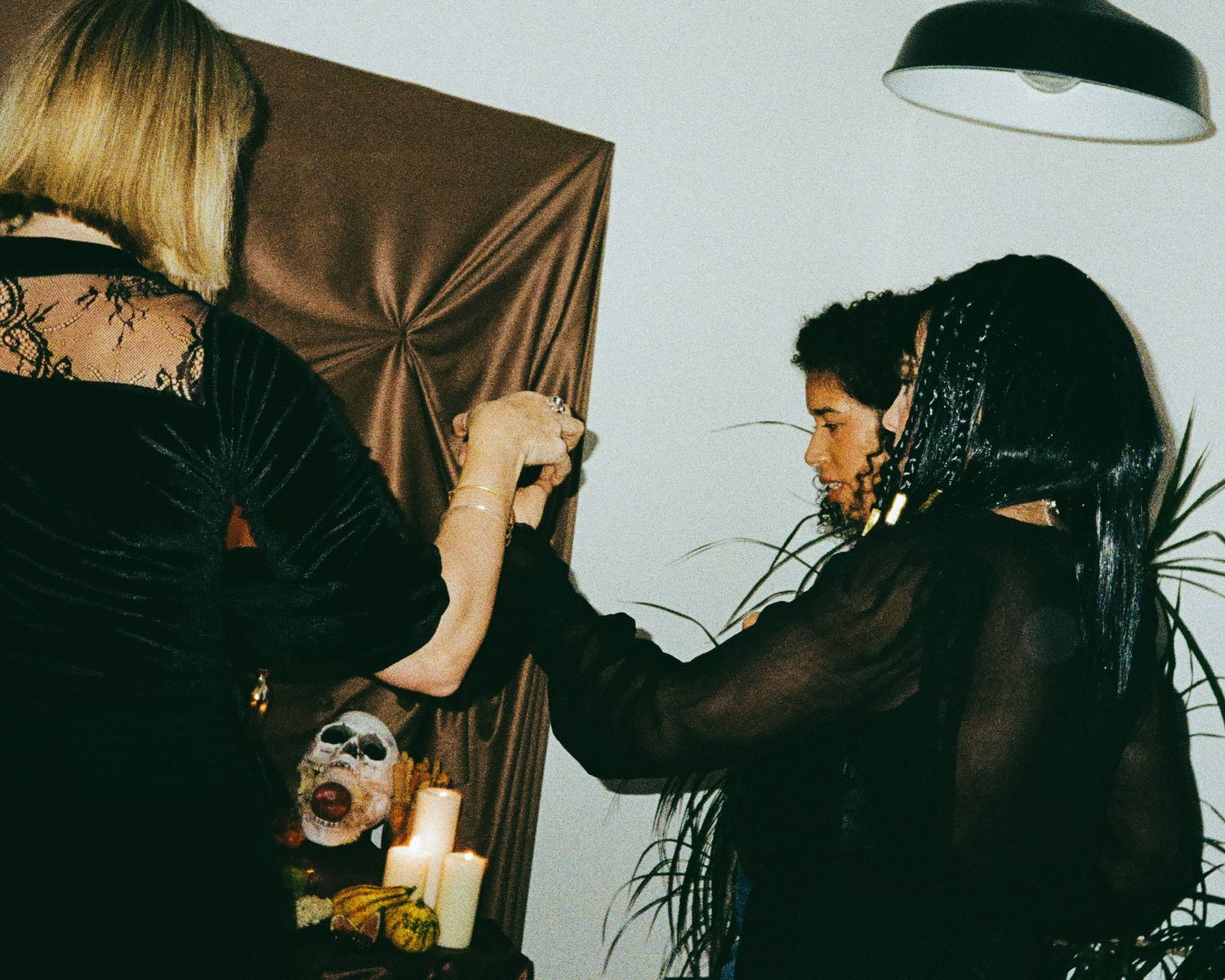 Blurred candlelit scene with dark figures in Halloween costumes moving through the frame.