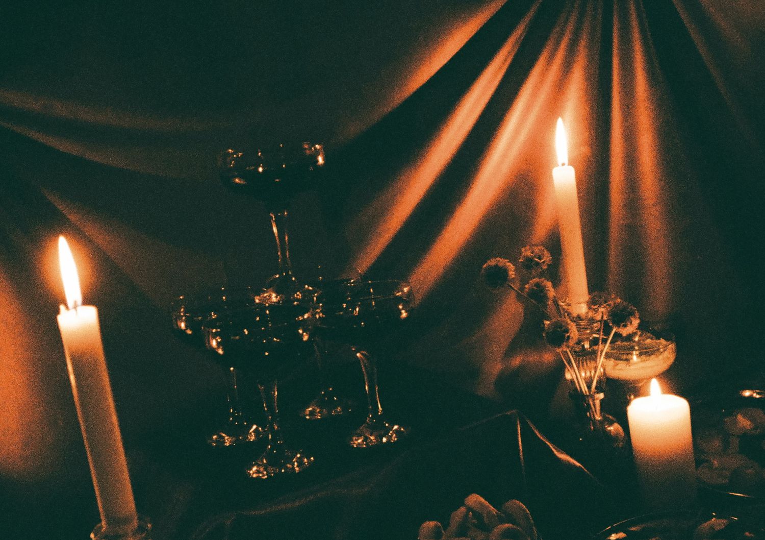 Moody candlelit scene with glowing ambiance against dark background.