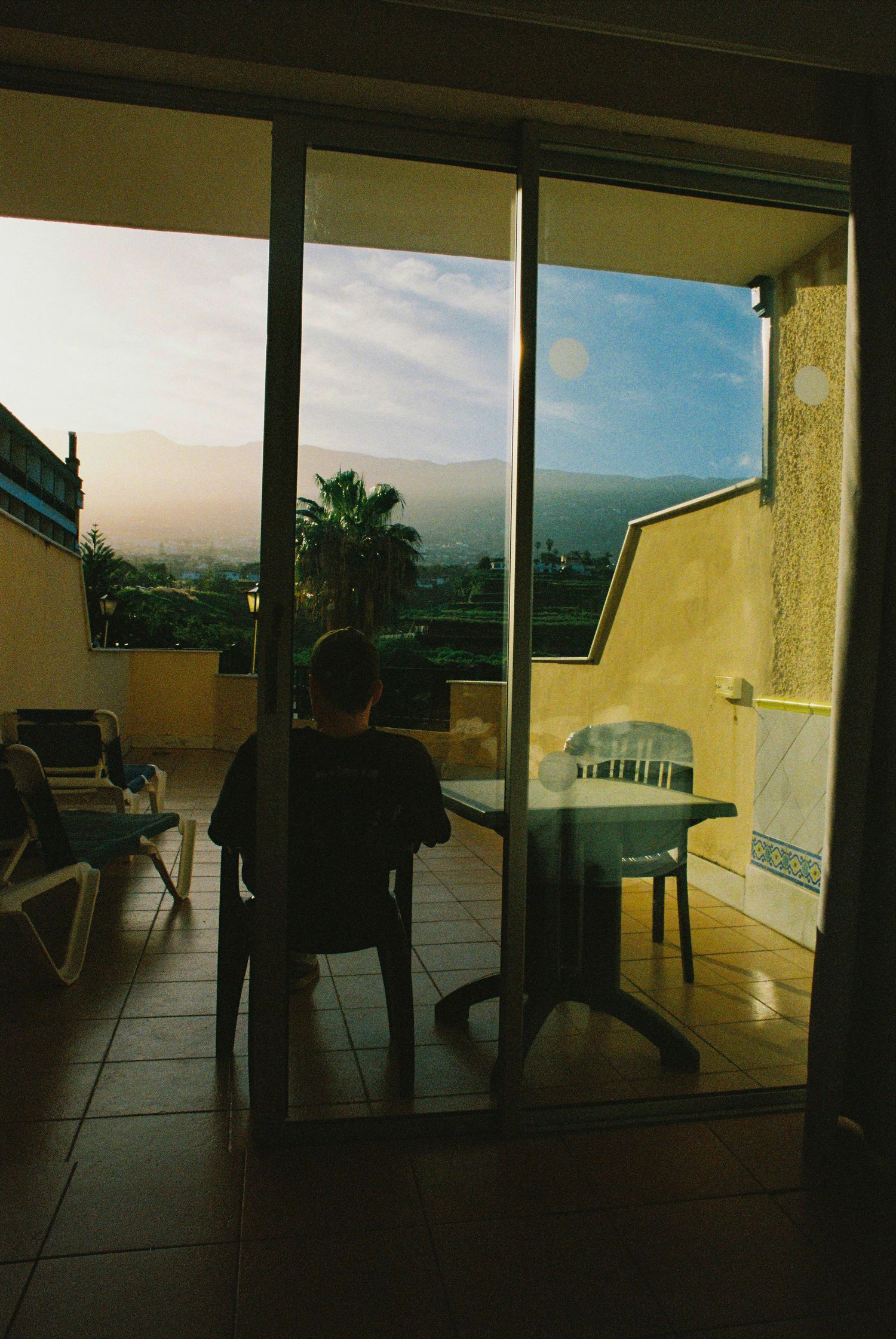 Panoramic view of a covered patio with chairs overlooking mountains at sunset.
