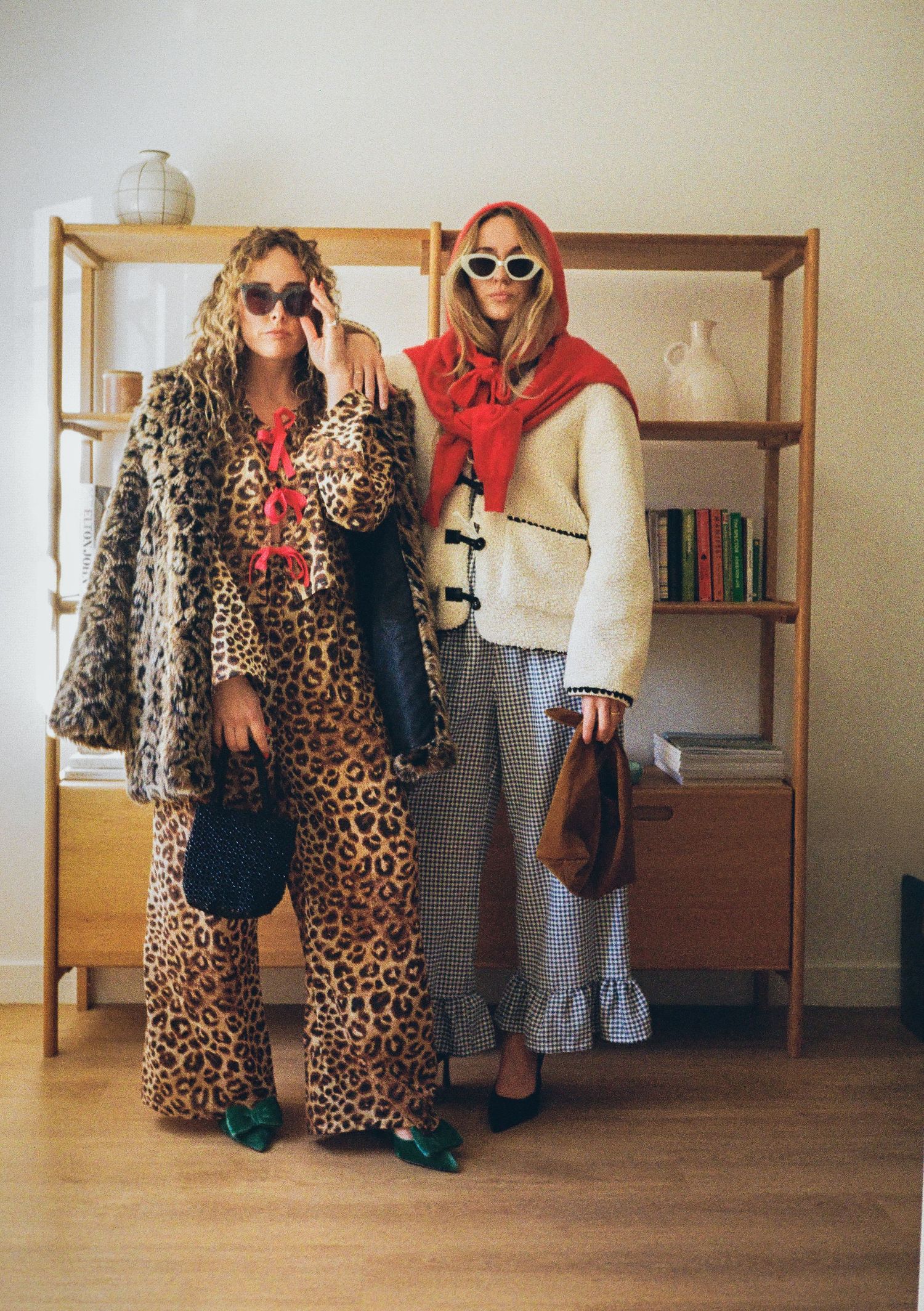 People wearing leopard print coats and sunglasses posing in a bright interior space.