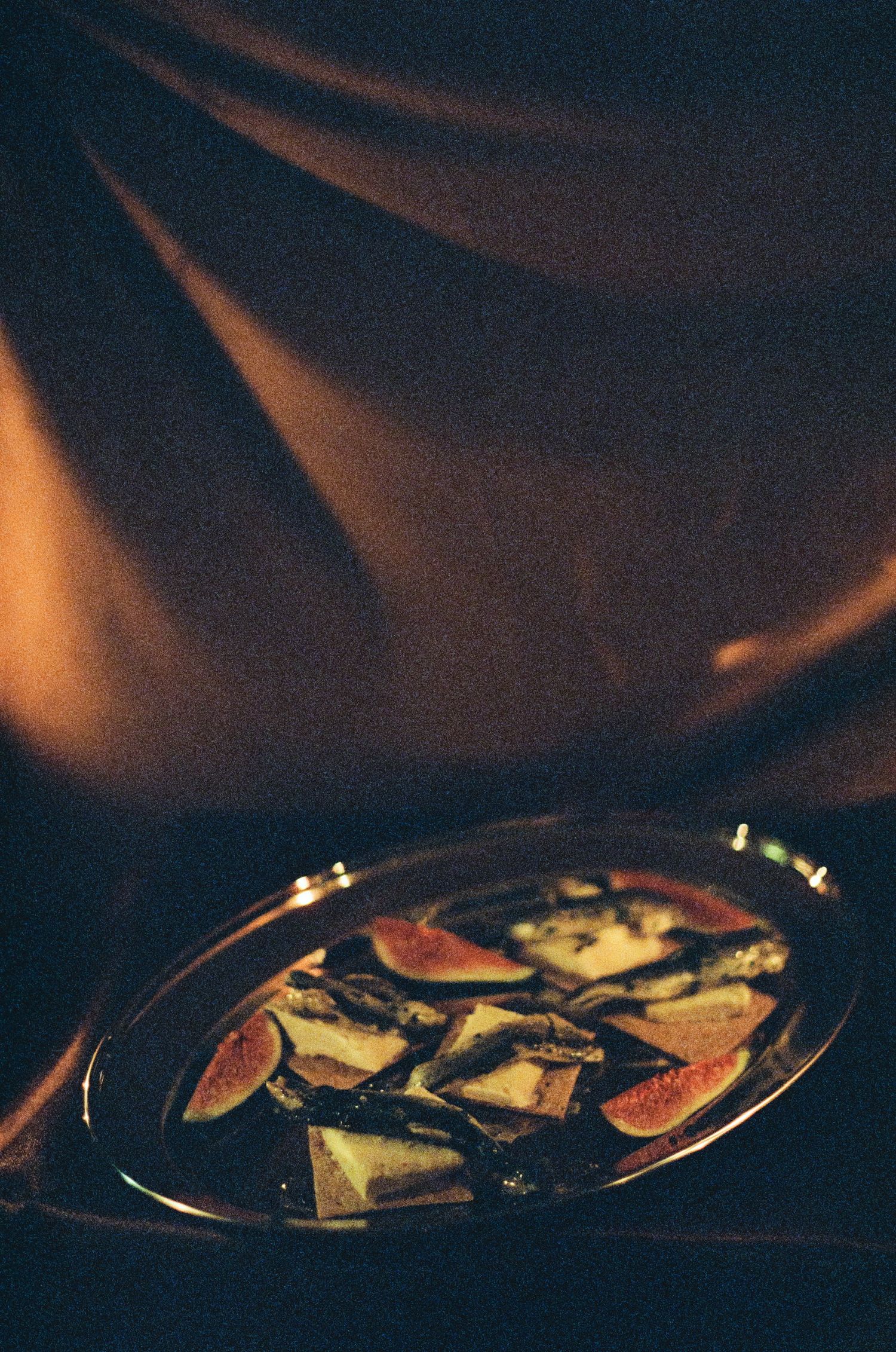 Dimly lit plates of food on dark table with moody Halloween ambiance.