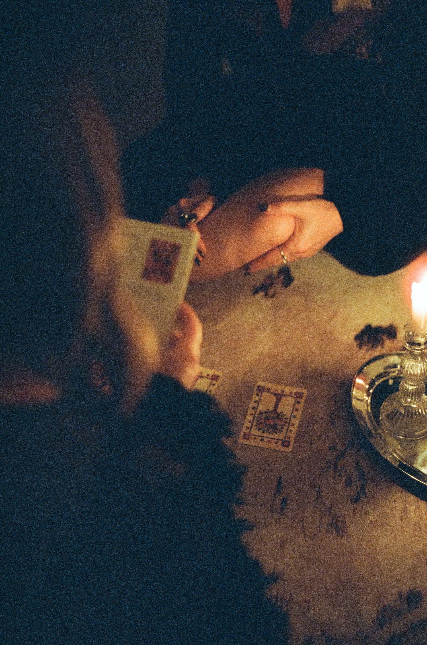 Playing cards illuminated by candlelight on dark table at Halloween gathering.
