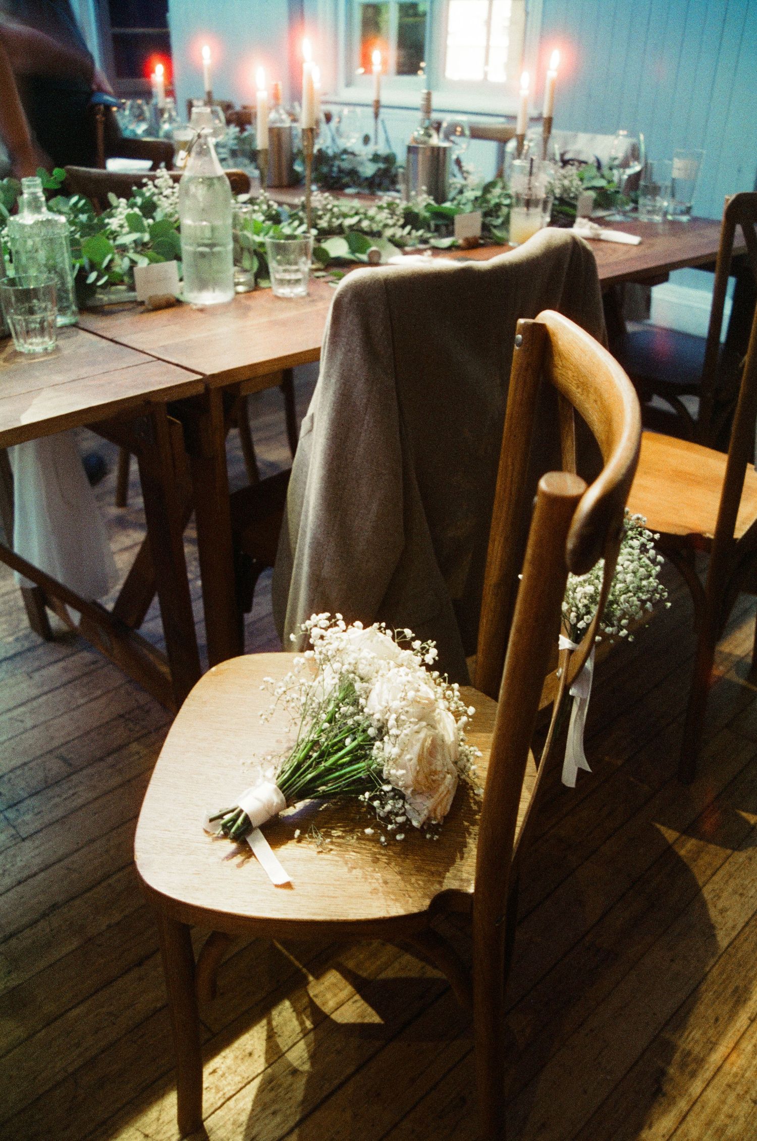 Wooden chairs decorated with baby's breath flowers in a rustic indoor setting.