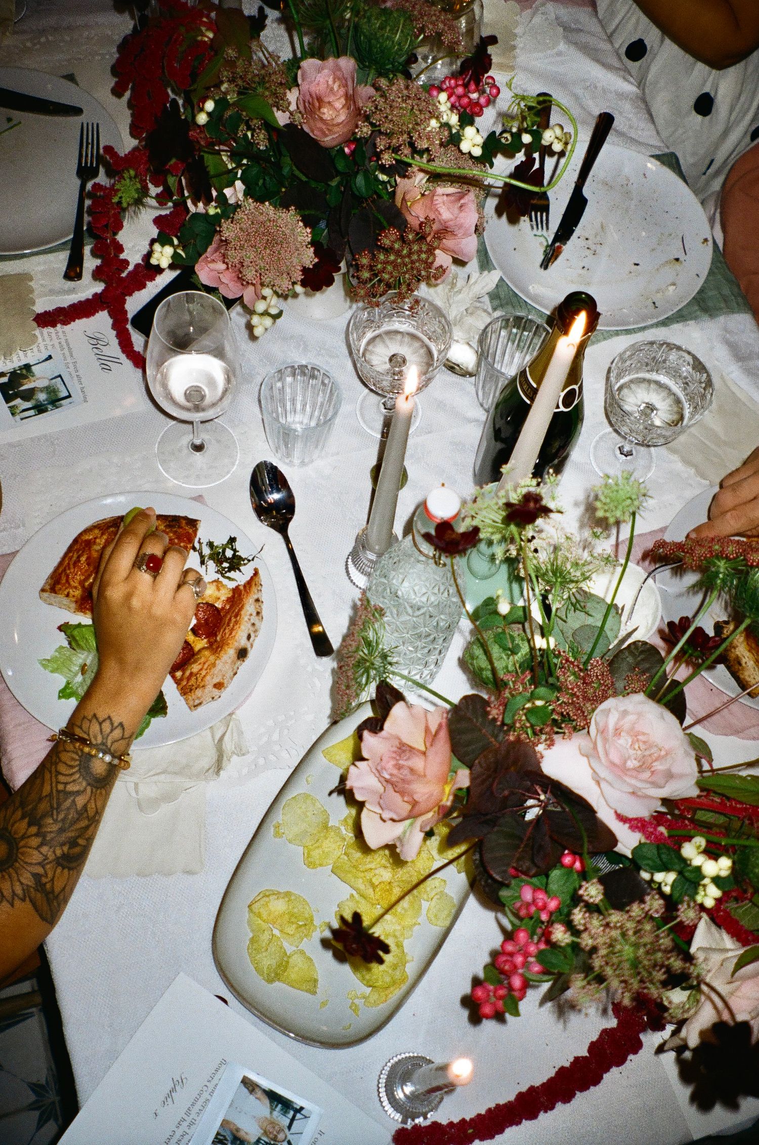 Overhead view of an elegant dinner table setting with pink flowers and candles.