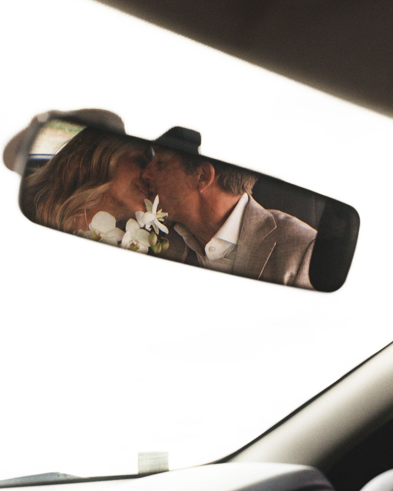 A creative wedding photo captured through a car's rearview mirror.