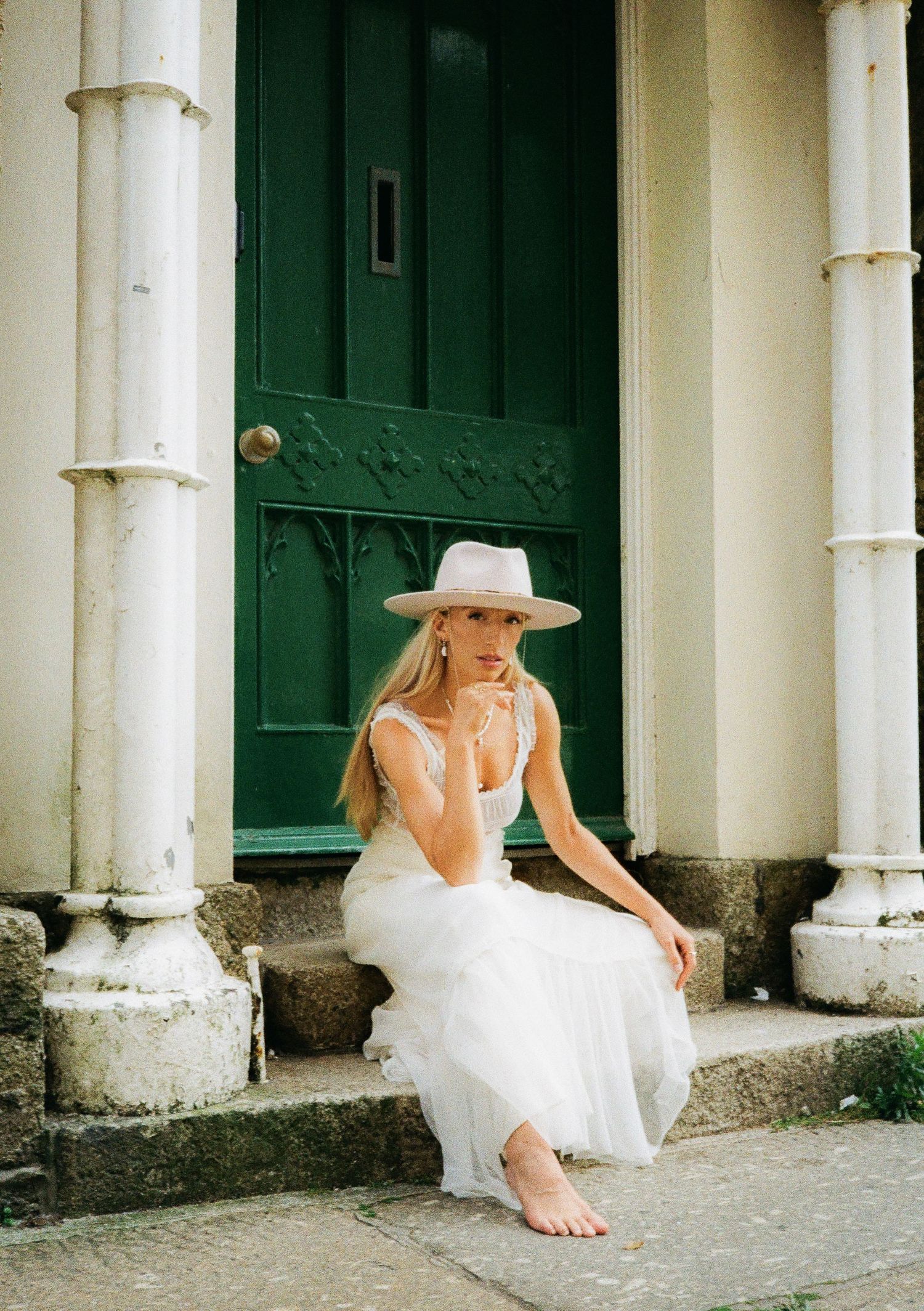 Artistic portraits on stone steps showing someone in a flowing white dress and beige hat.