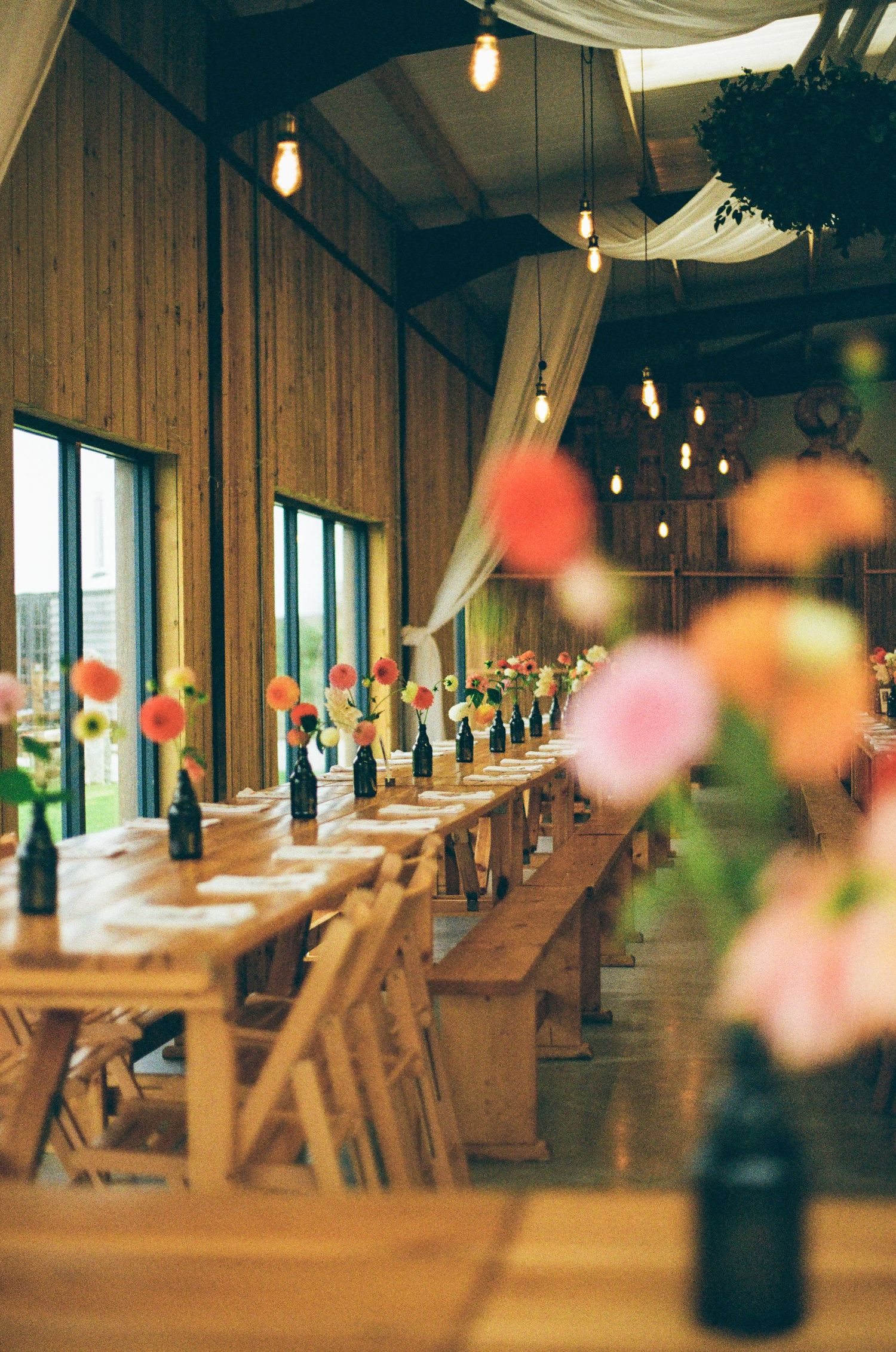 Rustic wooden reception venue with string lights and long tables set for a wedding celebration.