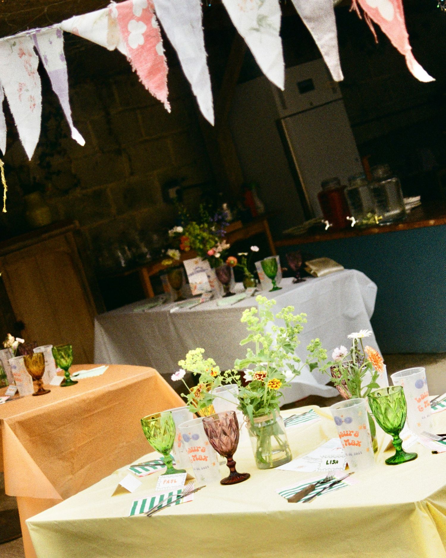 Wedding reception table setting with pink bunting flags and vintage glassware.