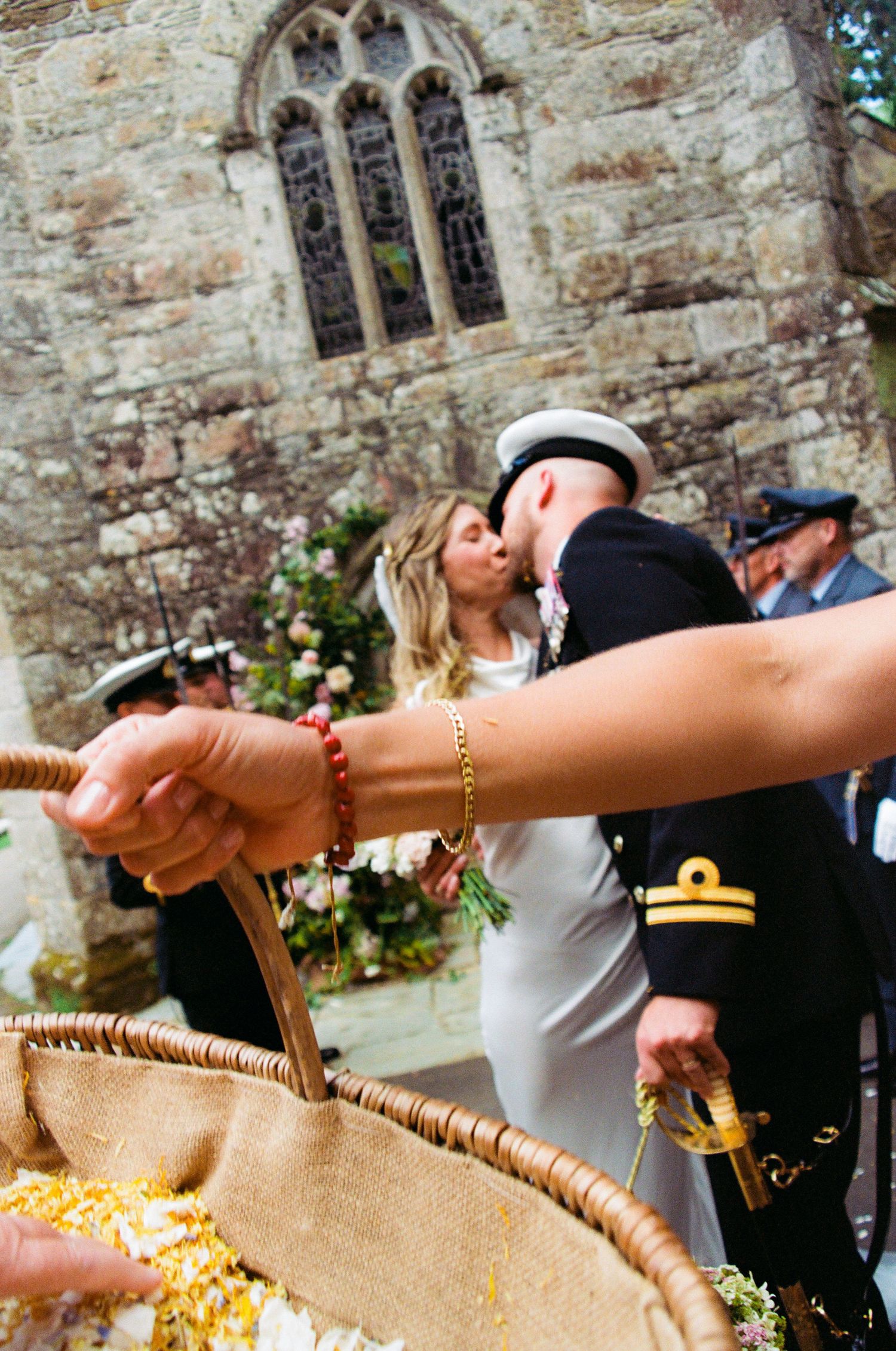 Wedding party gathering outside a historic stone church with gothic windows.