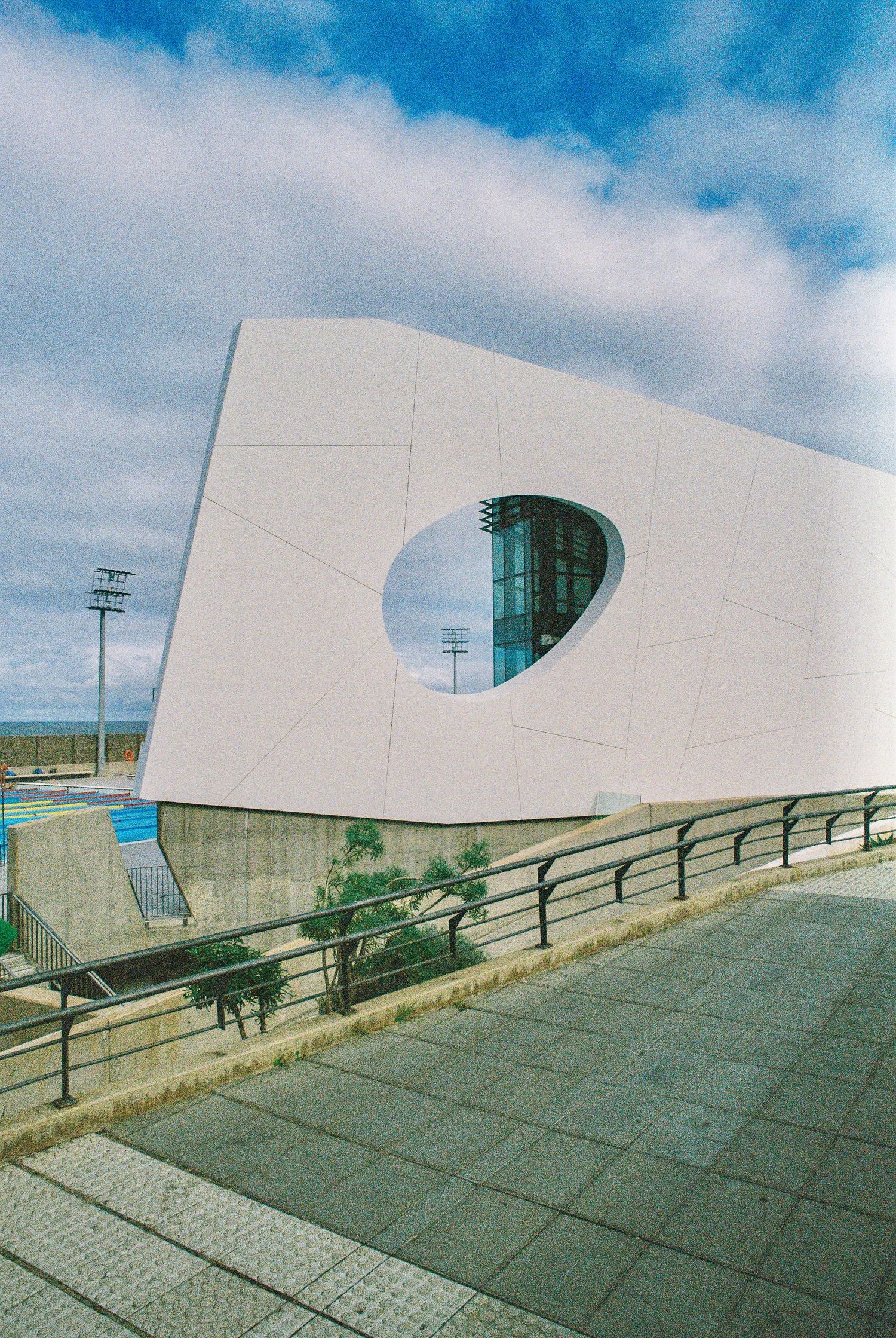 Curved white modern architectural structure against blue sky with geometric patterns.