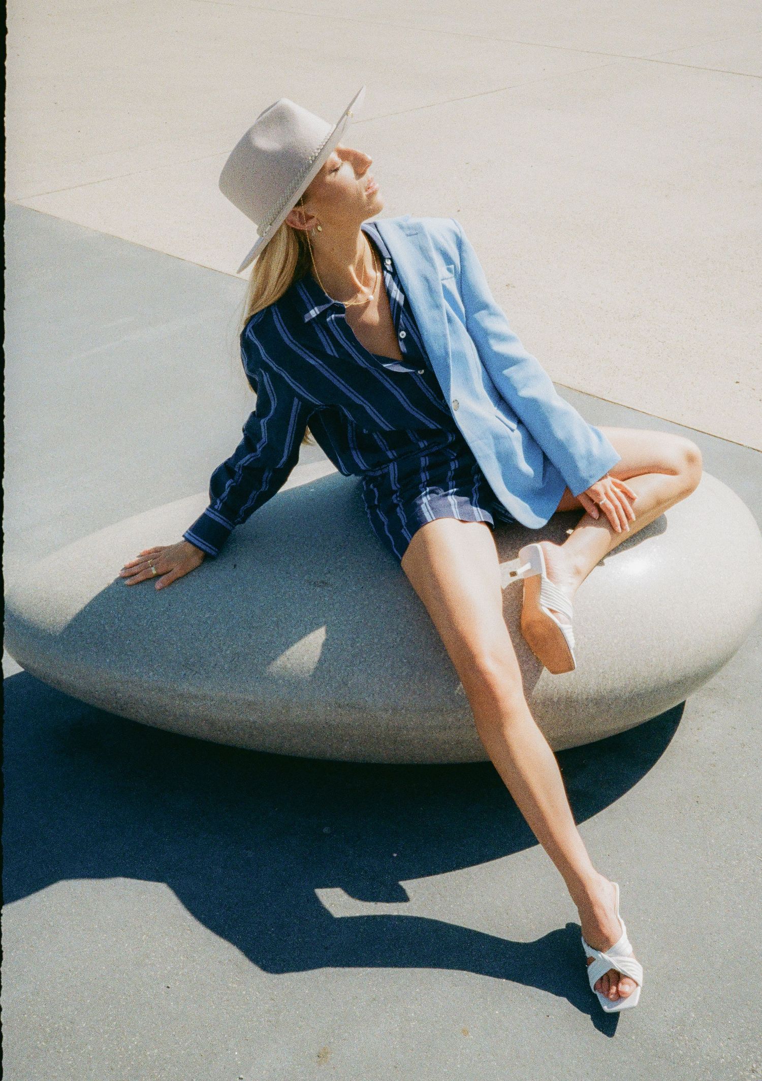 Fashion series featuring denim outfit and white hat with dramatic poses on concrete surface.