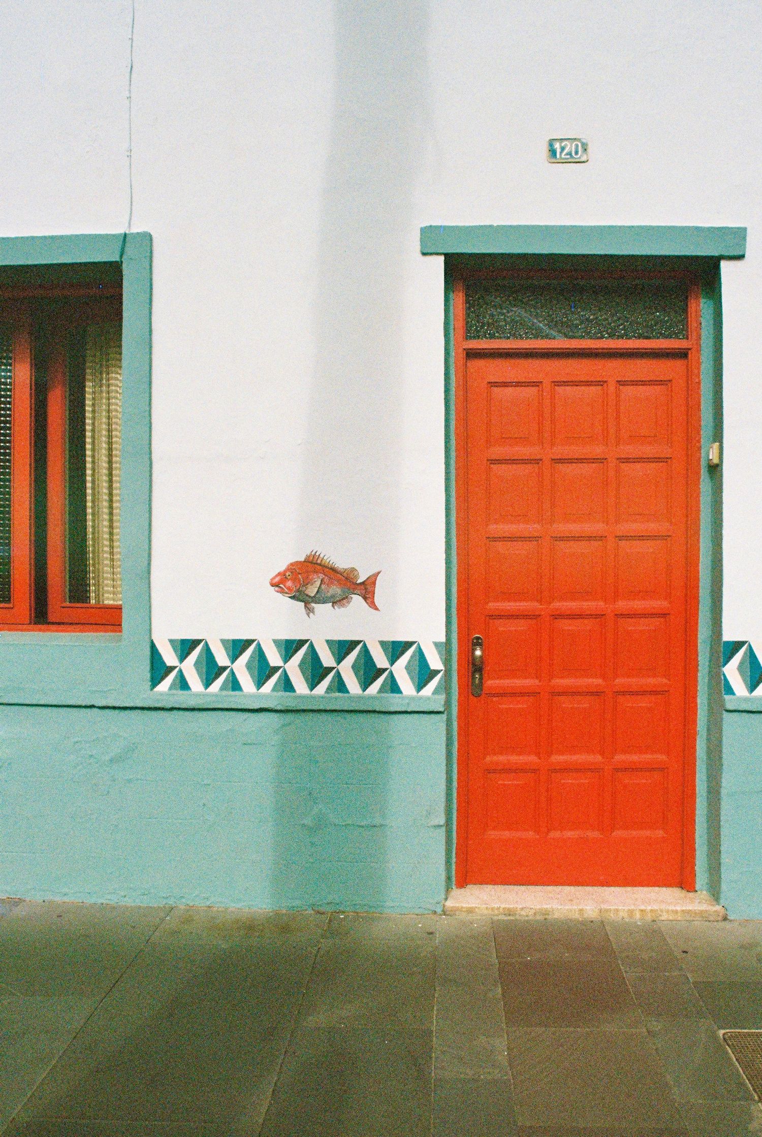 A series of white buildings with bright orange doors and turquoise trim creating a striking architectural pattern.