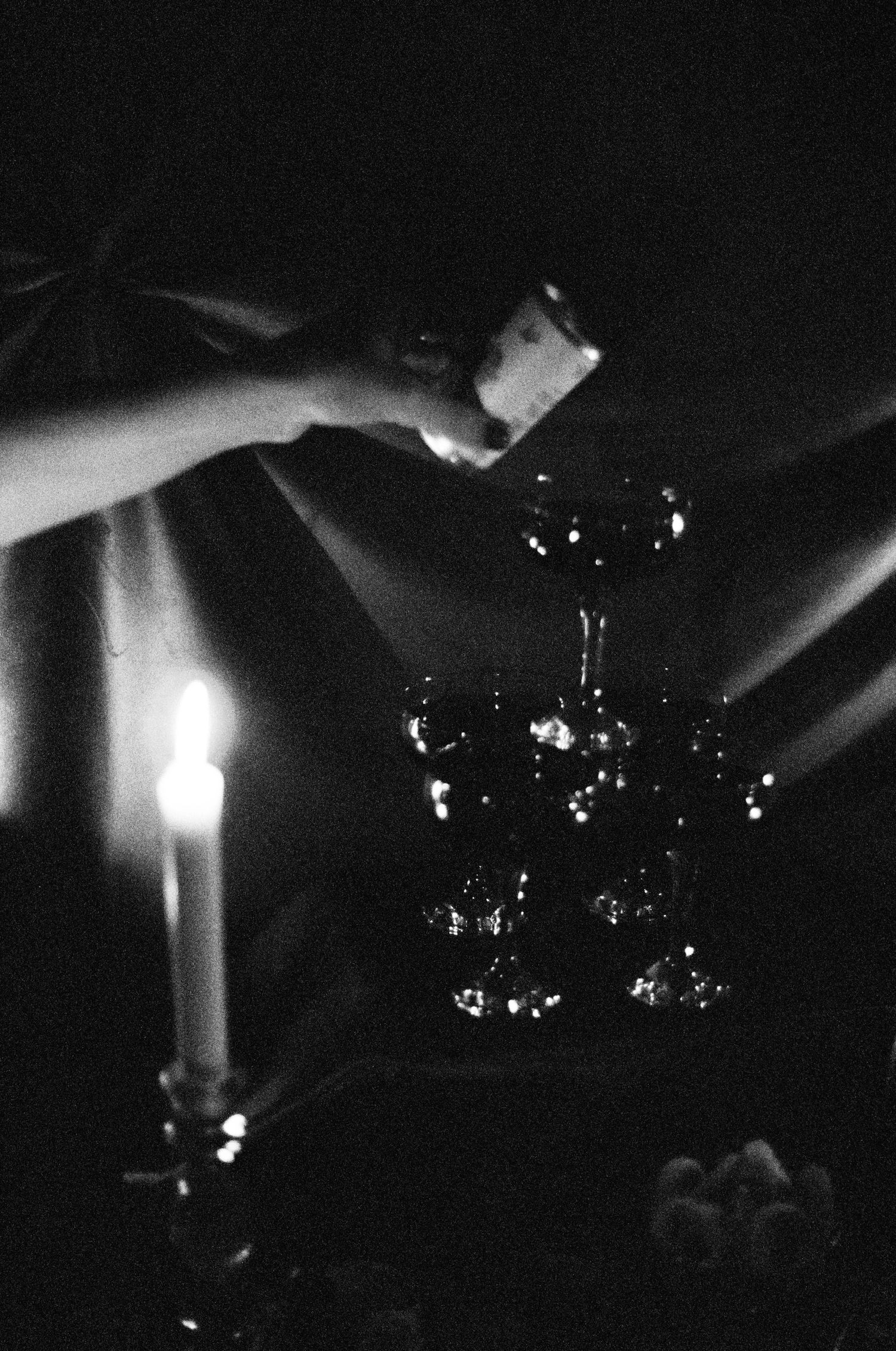 Black and white photo of candles glowing in darkness with ethereal light patterns.