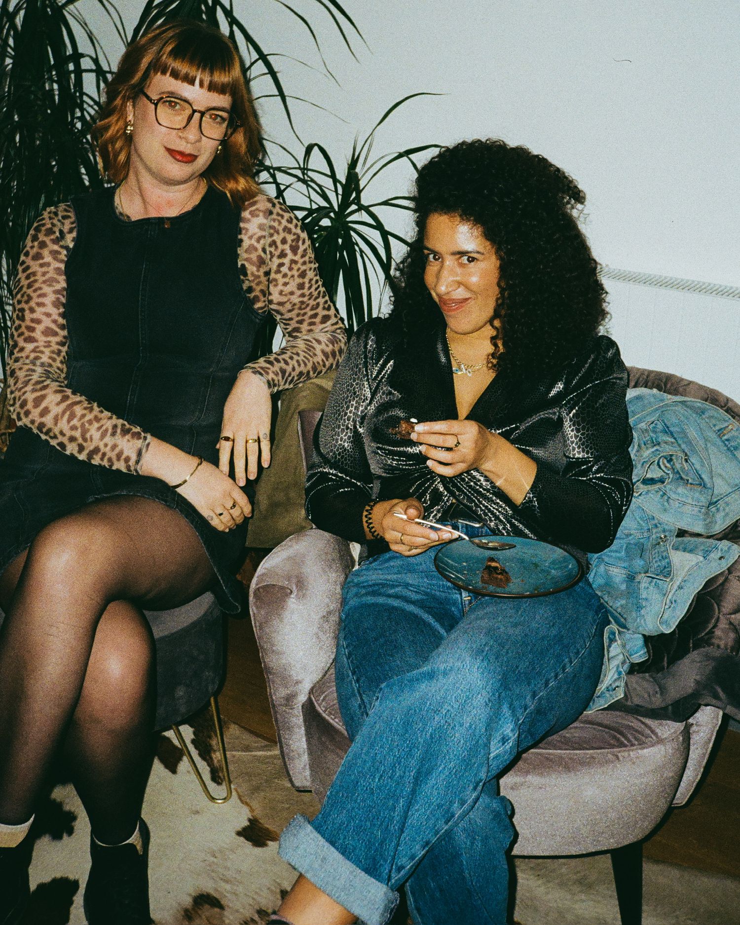 Friends relaxing on a gray armchair during an indoor gathering.