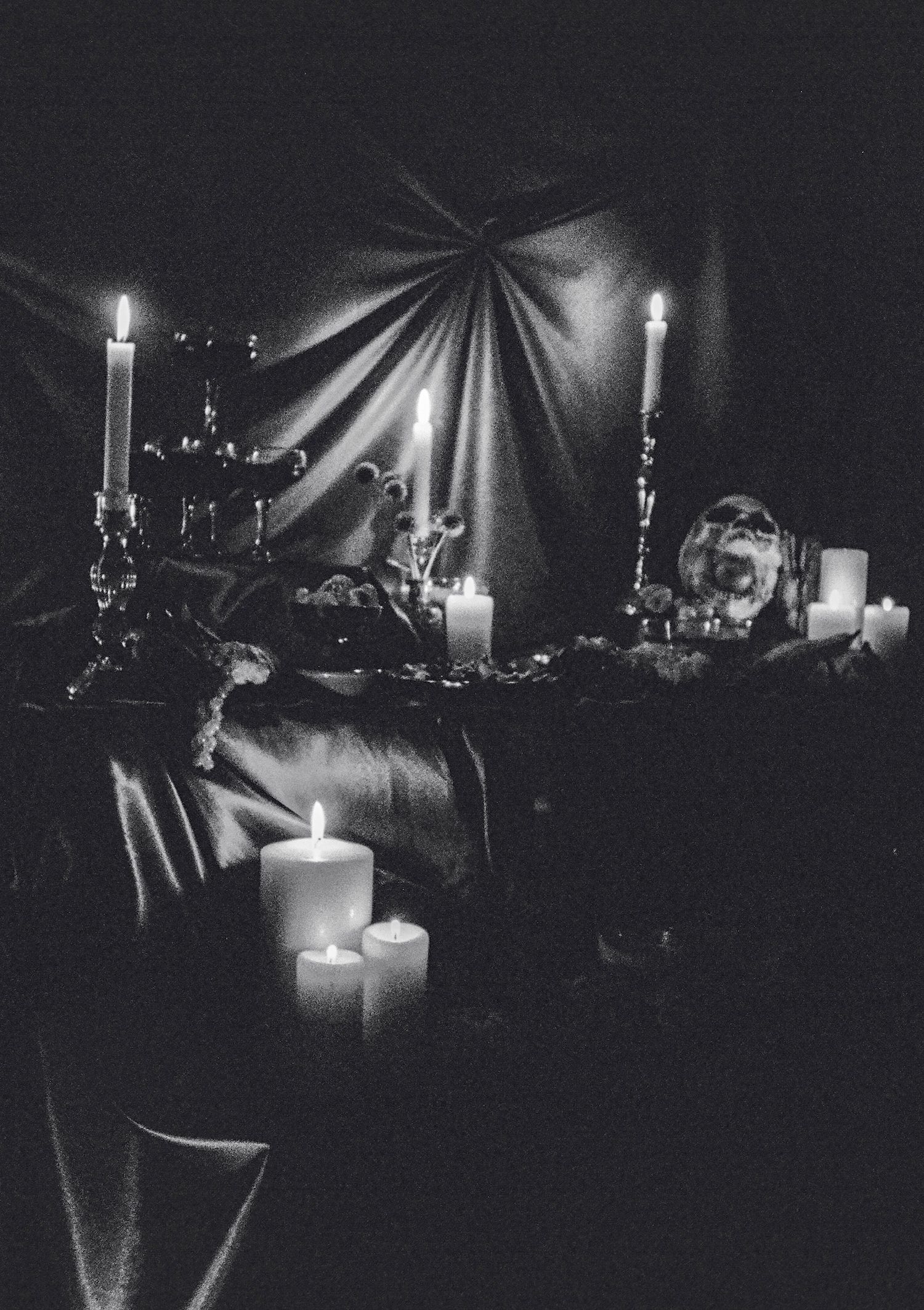 Dark atmospheric scene with candles creating dramatic shadows and light patterns.