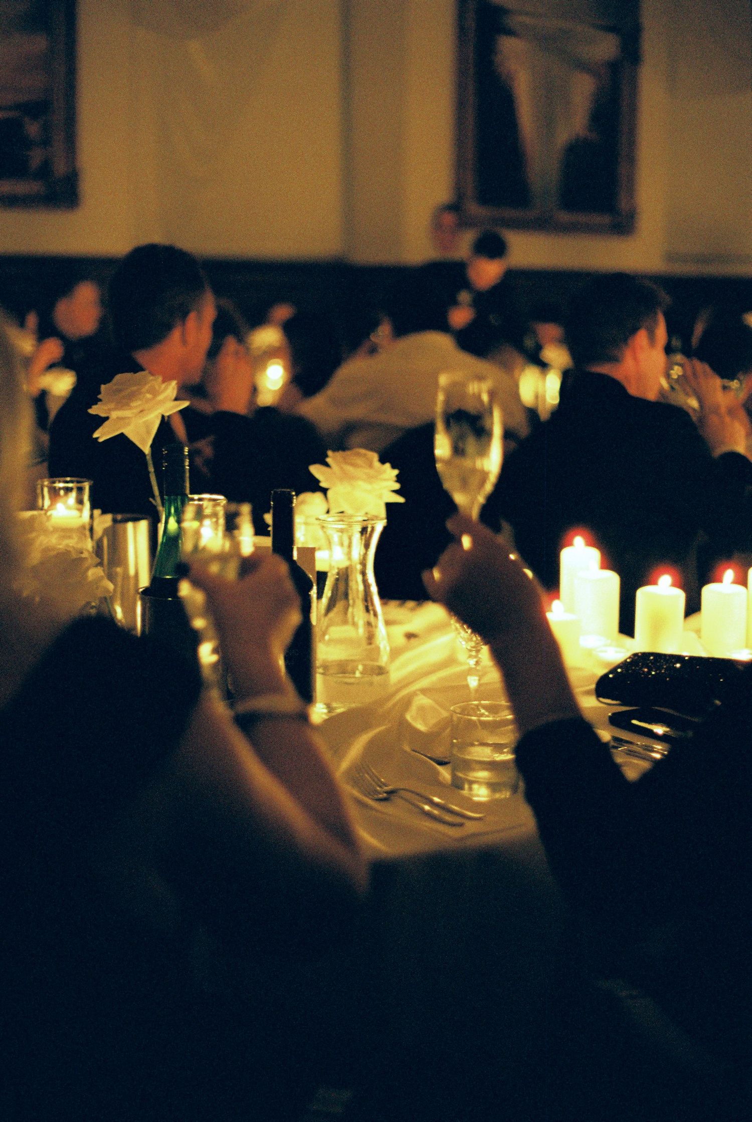Soft candlelight illuminates elegant table settings at an evening wedding reception.