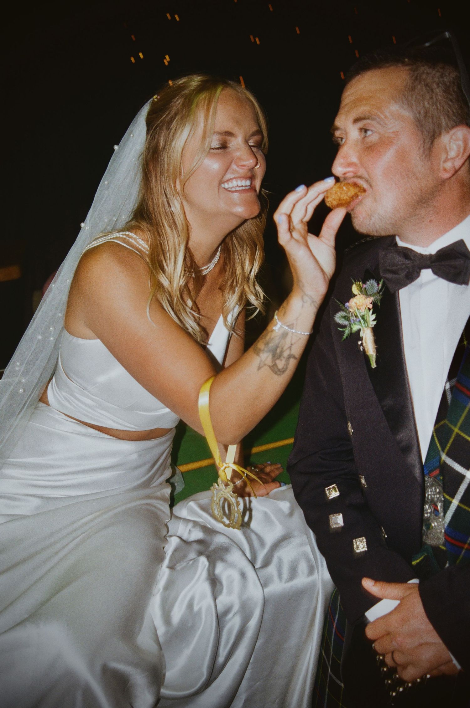 Playful wedding couple sharing cake during their reception celebration.