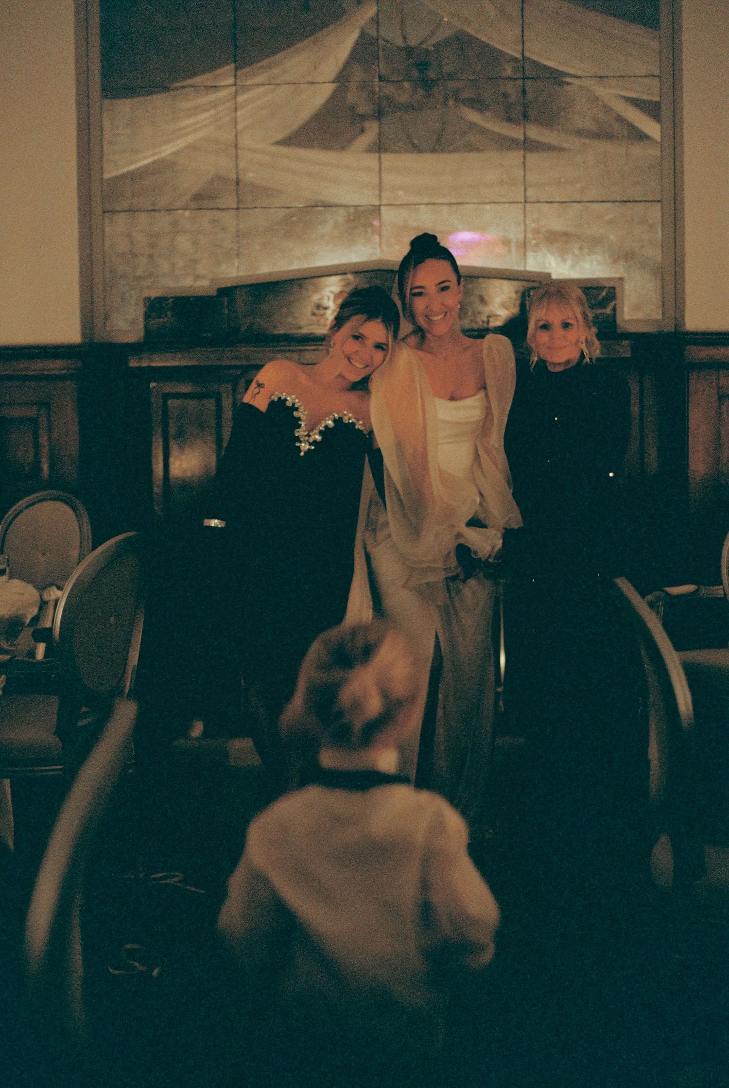 Wedding guests dance together in a dimly lit reception venue creating a joyful atmosphere.