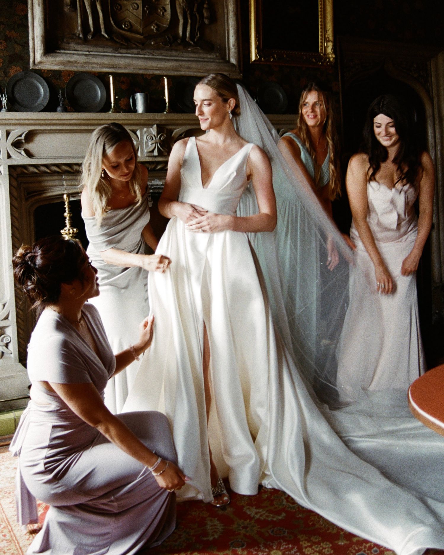 Bridesmaids in white dresses helping with wedding preparations in an elegant room.