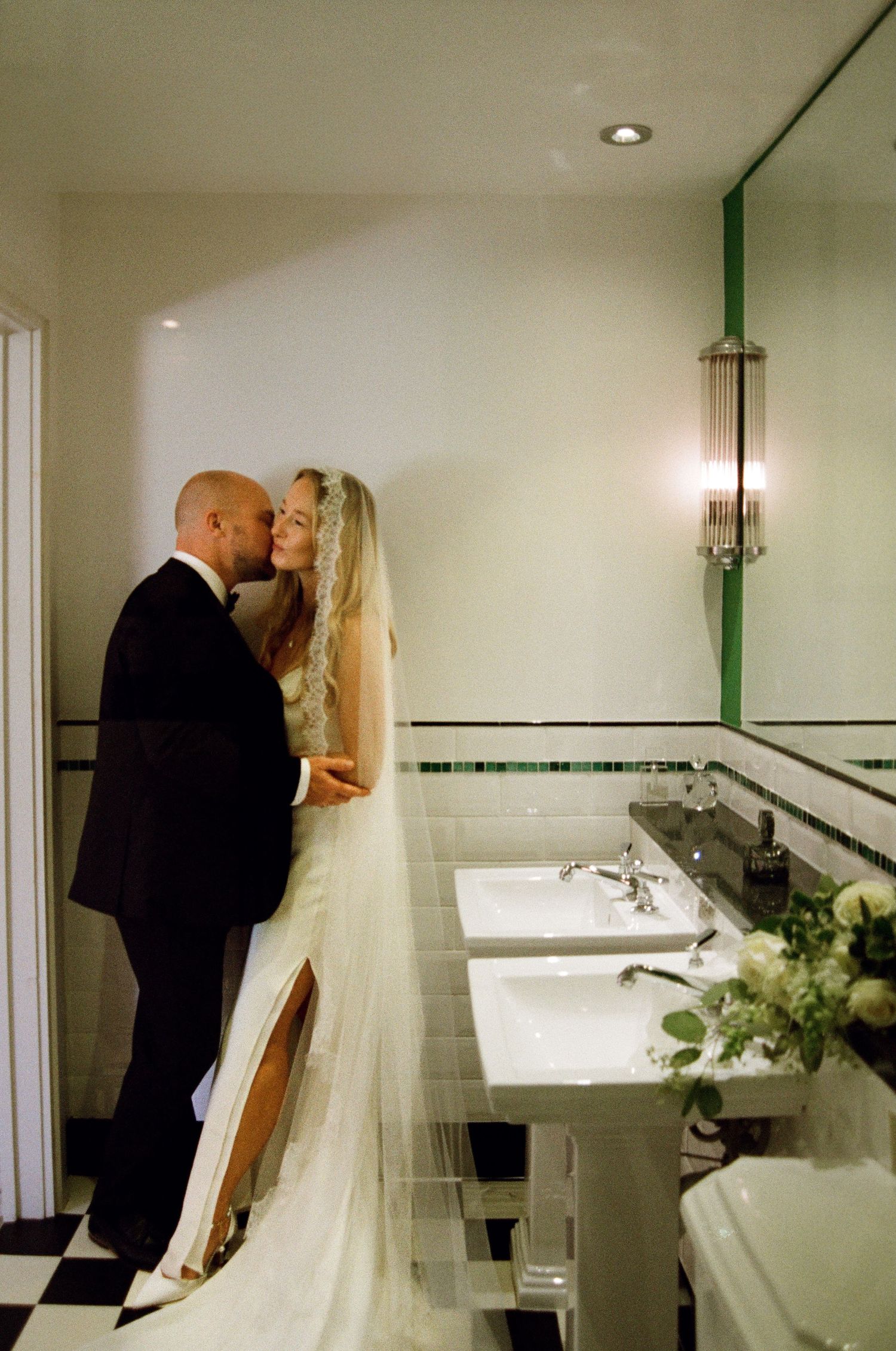 An intimate wedding moment captured in an elegant black and white tiled bathroom.