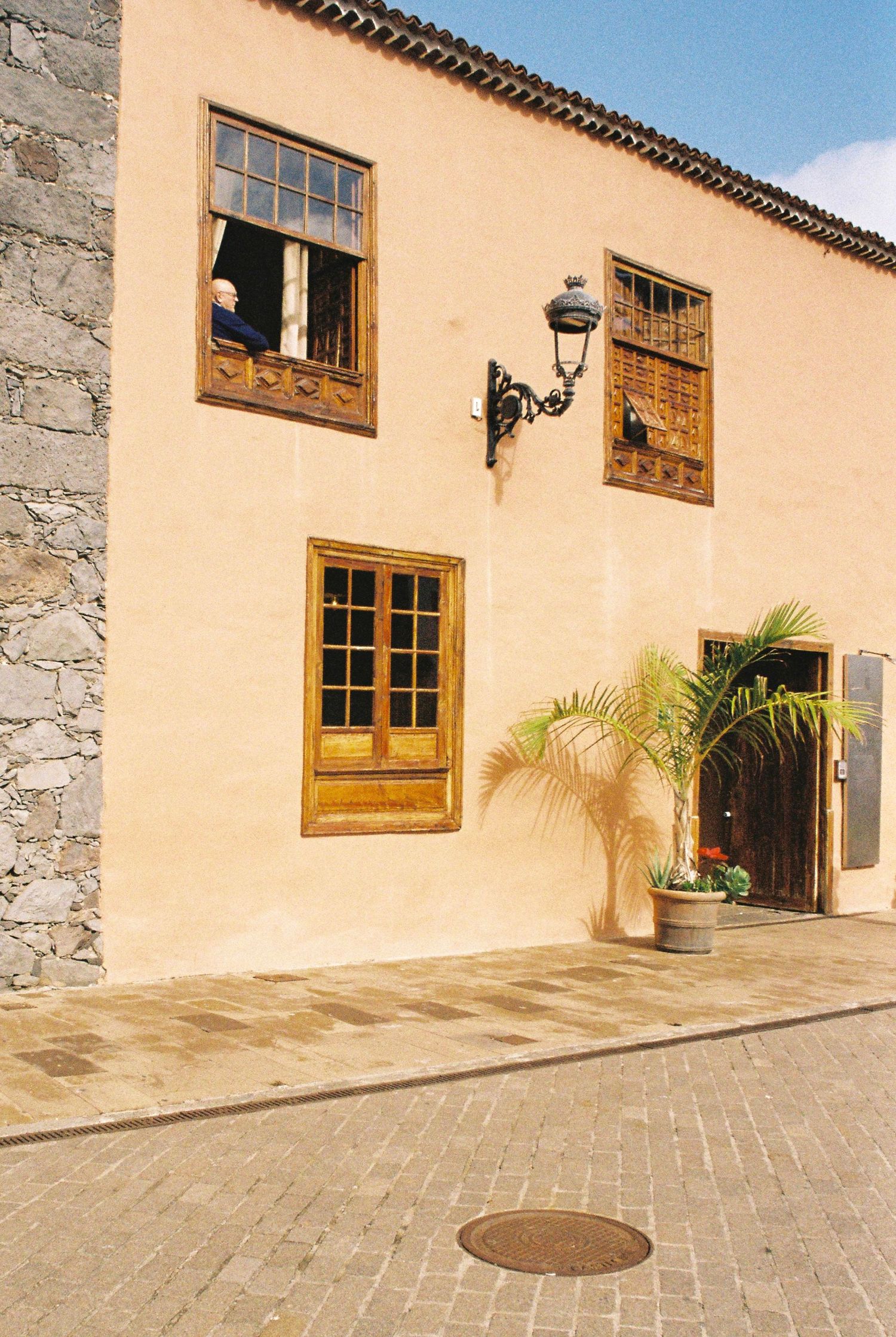 Beige stucco building with wooden windows and stone accents in Spanish colonial style.