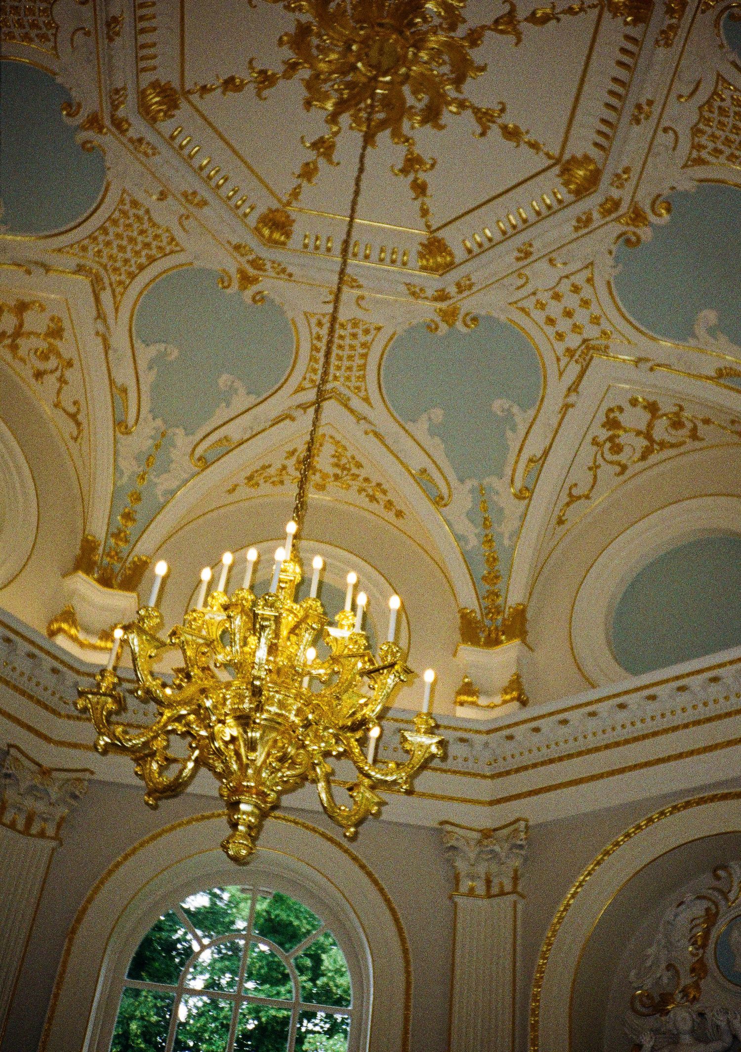 Ornate baroque ceiling with gold details and crystal chandeliers in a grand room.