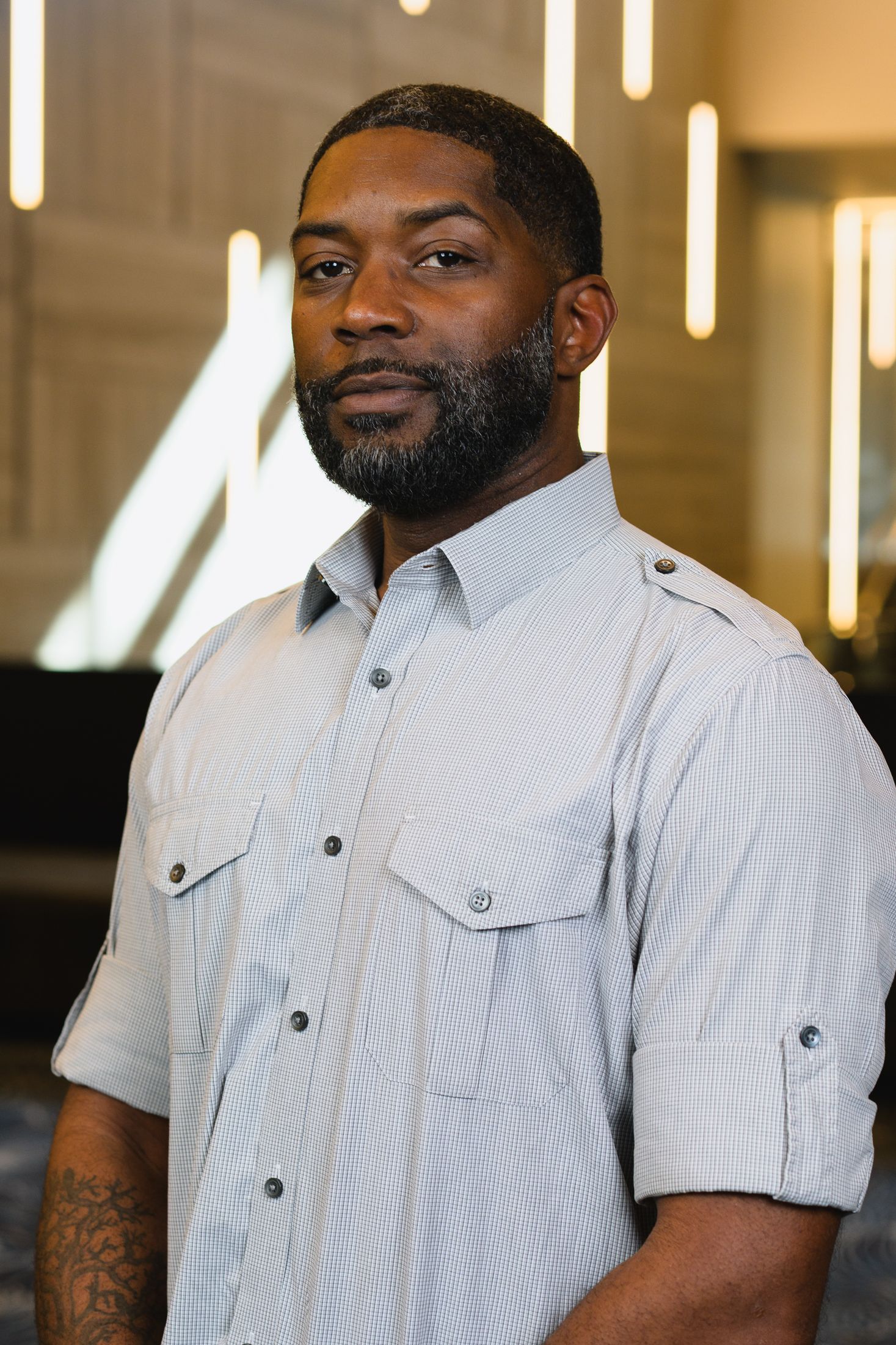 Professional portrait of someone wearing a white button-down shirt with pockets in an office environment.