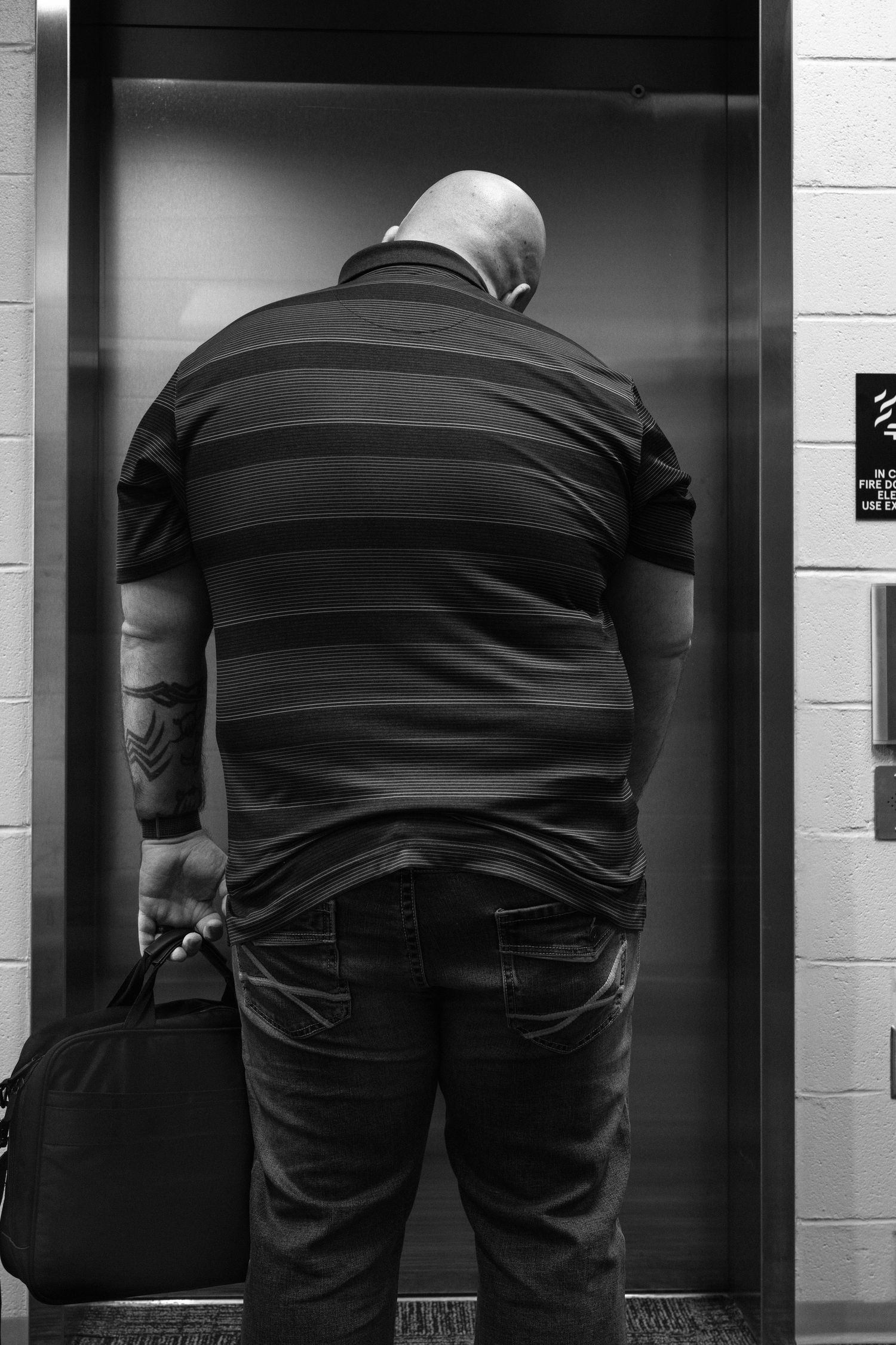 Black and white photo sequence showing a person bending over to look through multiple elevator doors.