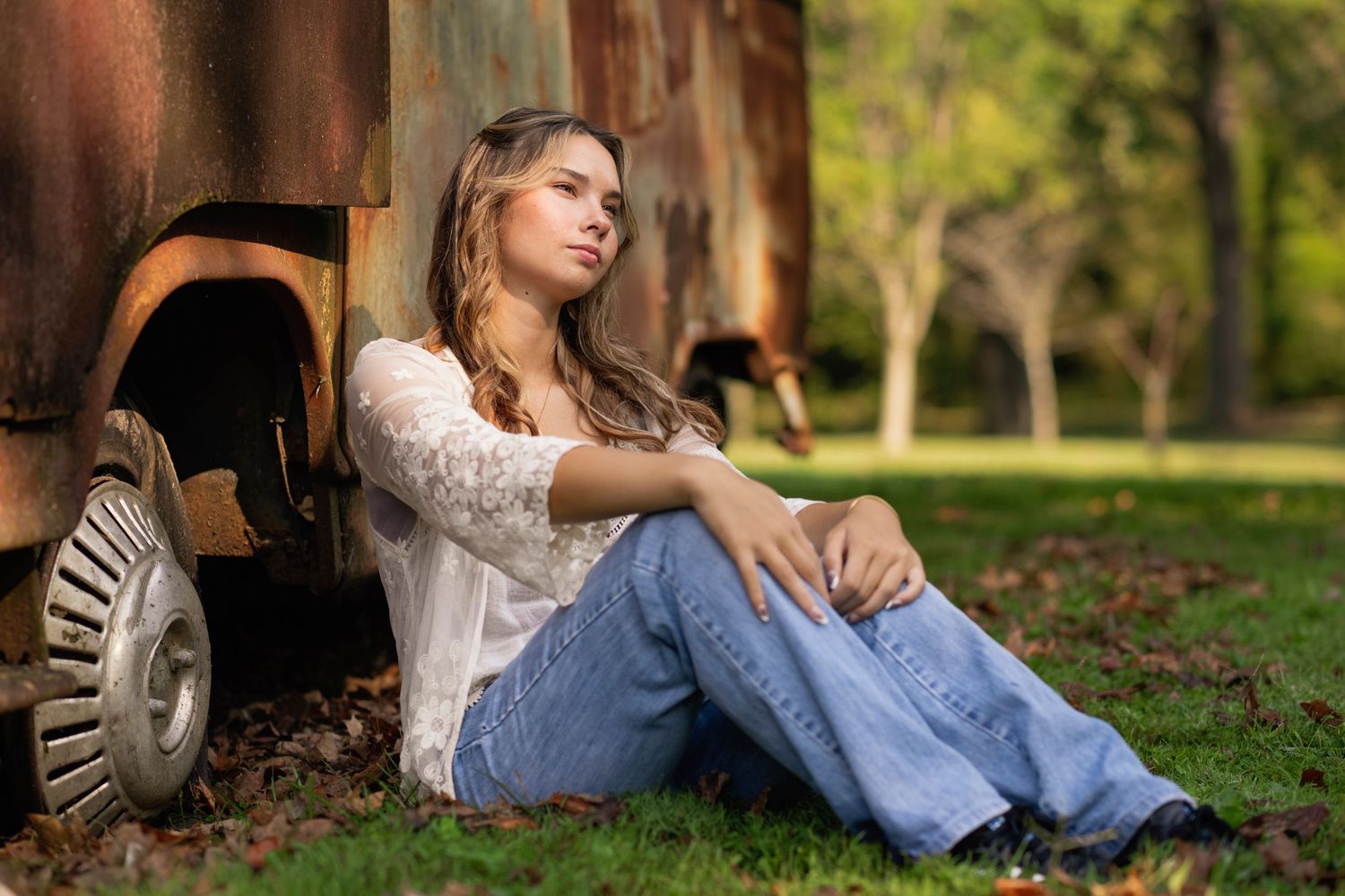 A series of outdoor portrait photos showing someone in casual wear sitting on grass in a sunlit park setting.