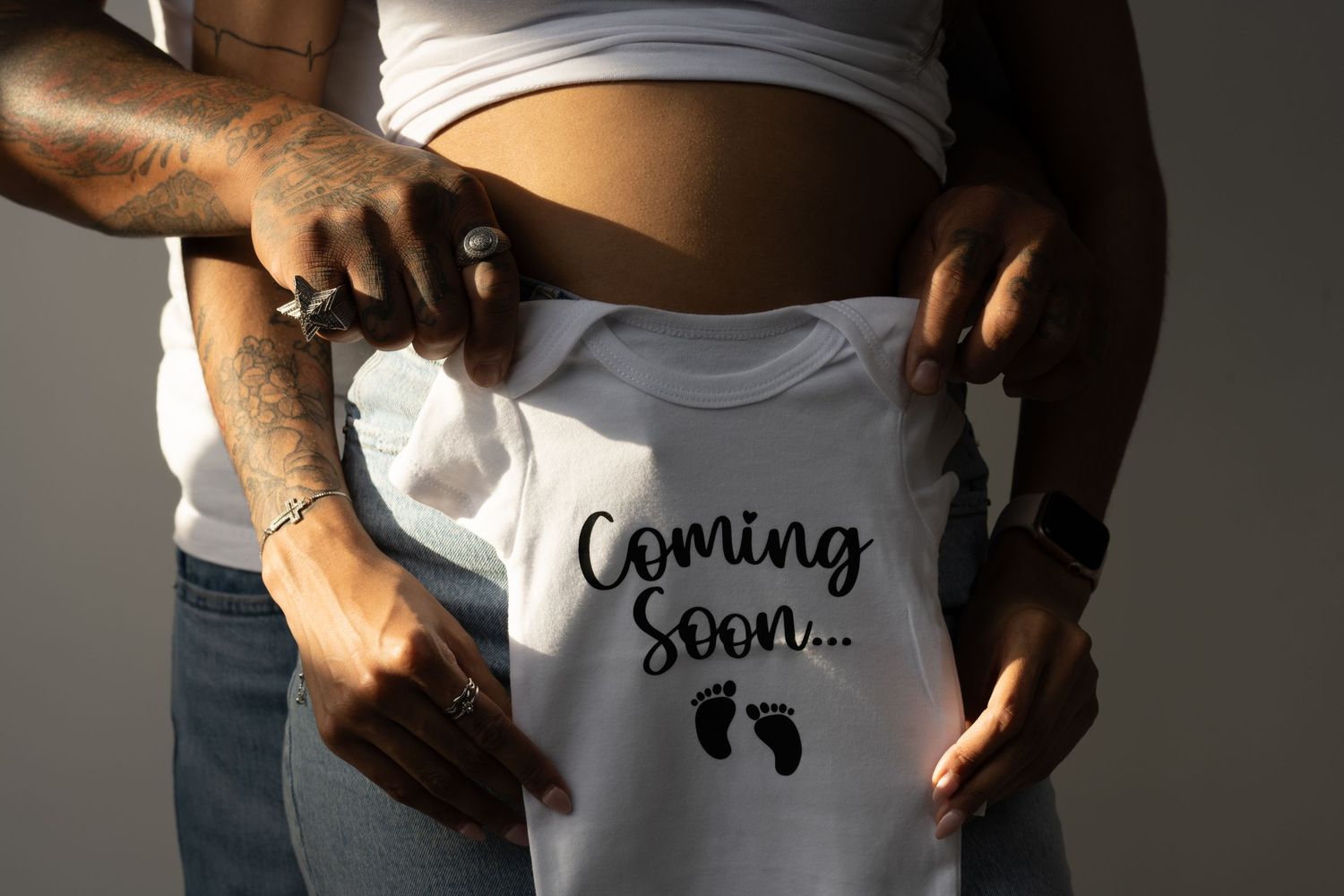 Close-up of white maternity shirt with text revealing pregnancy announcement.