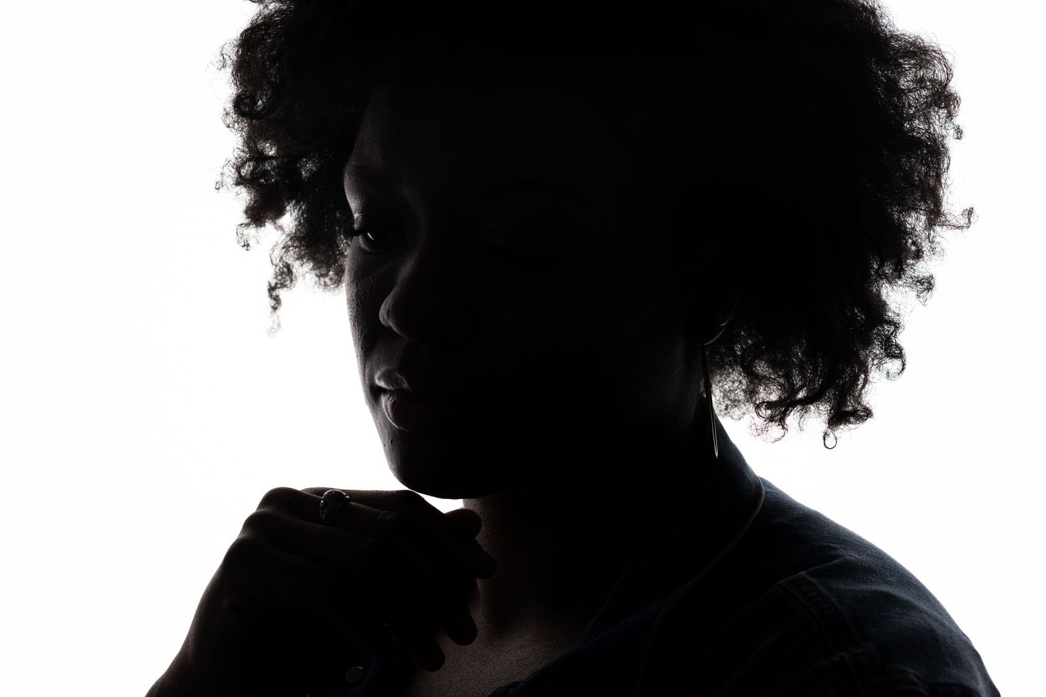 Dramatic side profile silhouette with curly hair against white background.