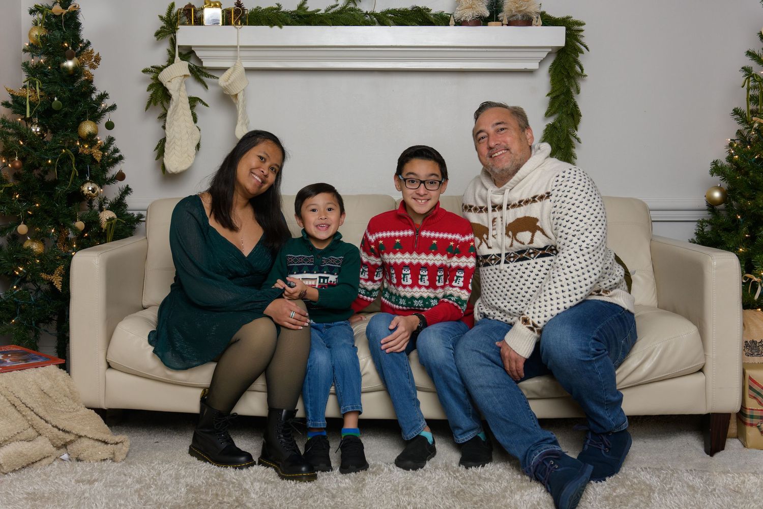 Holiday family photo on couch with Christmas decorations and matching sweaters.